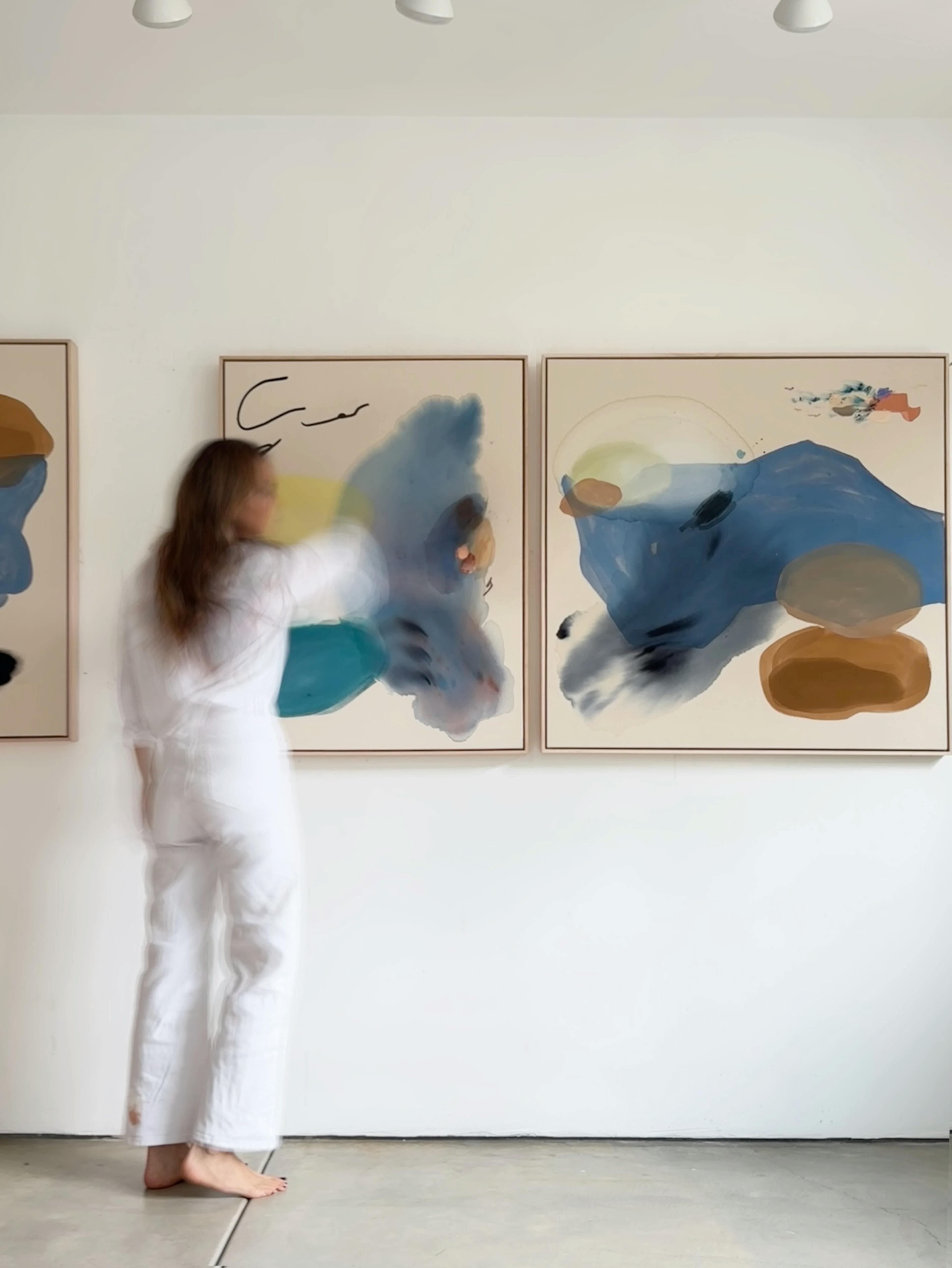 Artist Karina Bania blurred and standing in front of her gestural paintings.