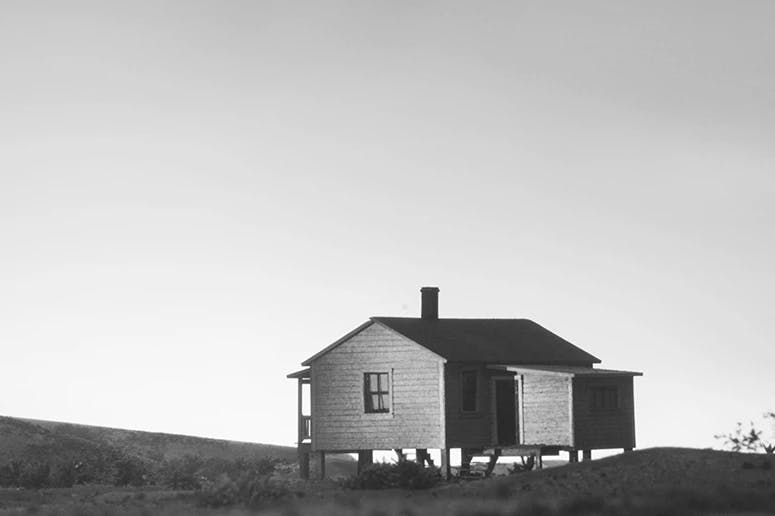 Black and white photograph by artist Bill Finger of a home within a deserted landscape.