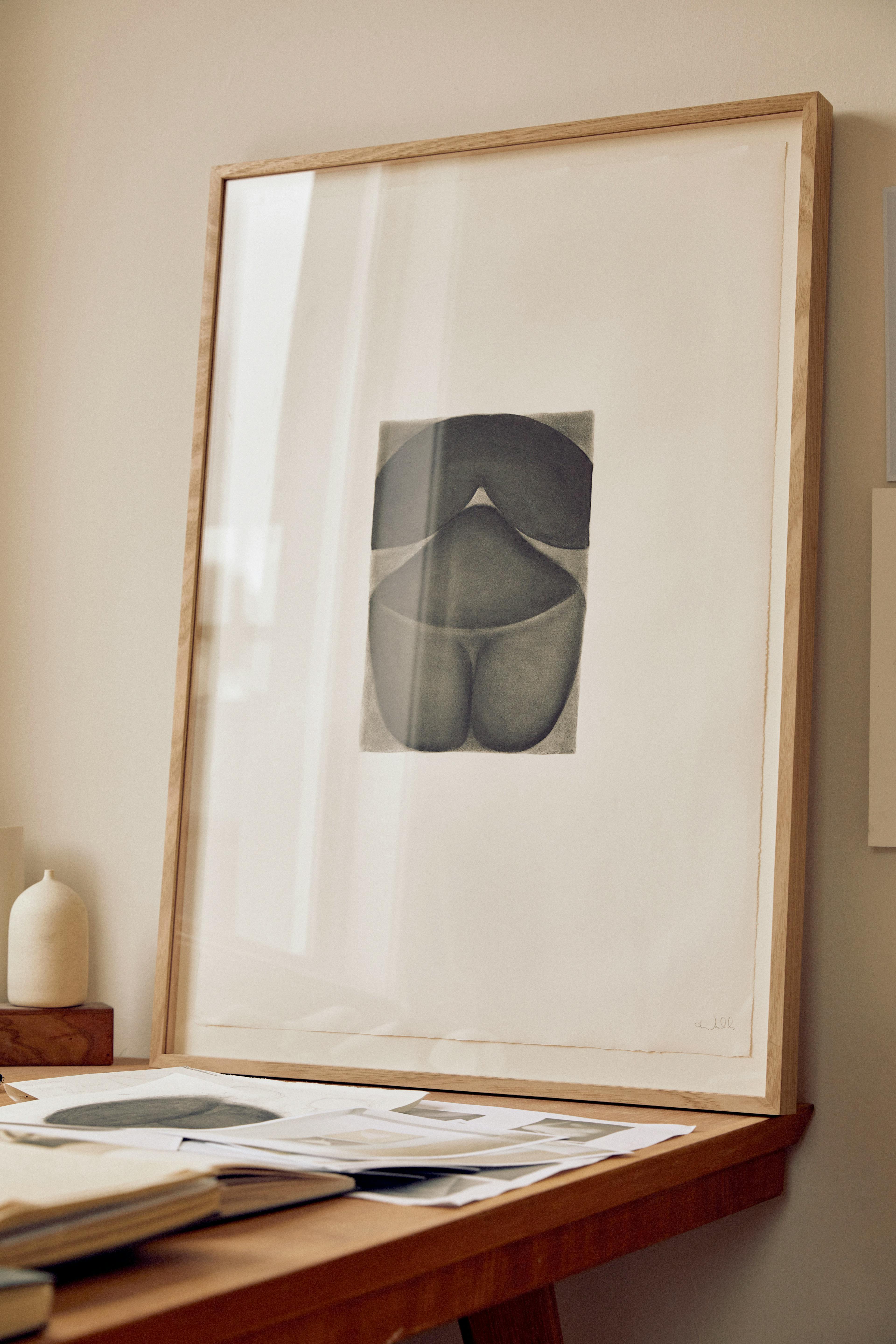 A charcoal drawing of an abstract figure framed in wood sits on a table at Caroline Walls' studio.