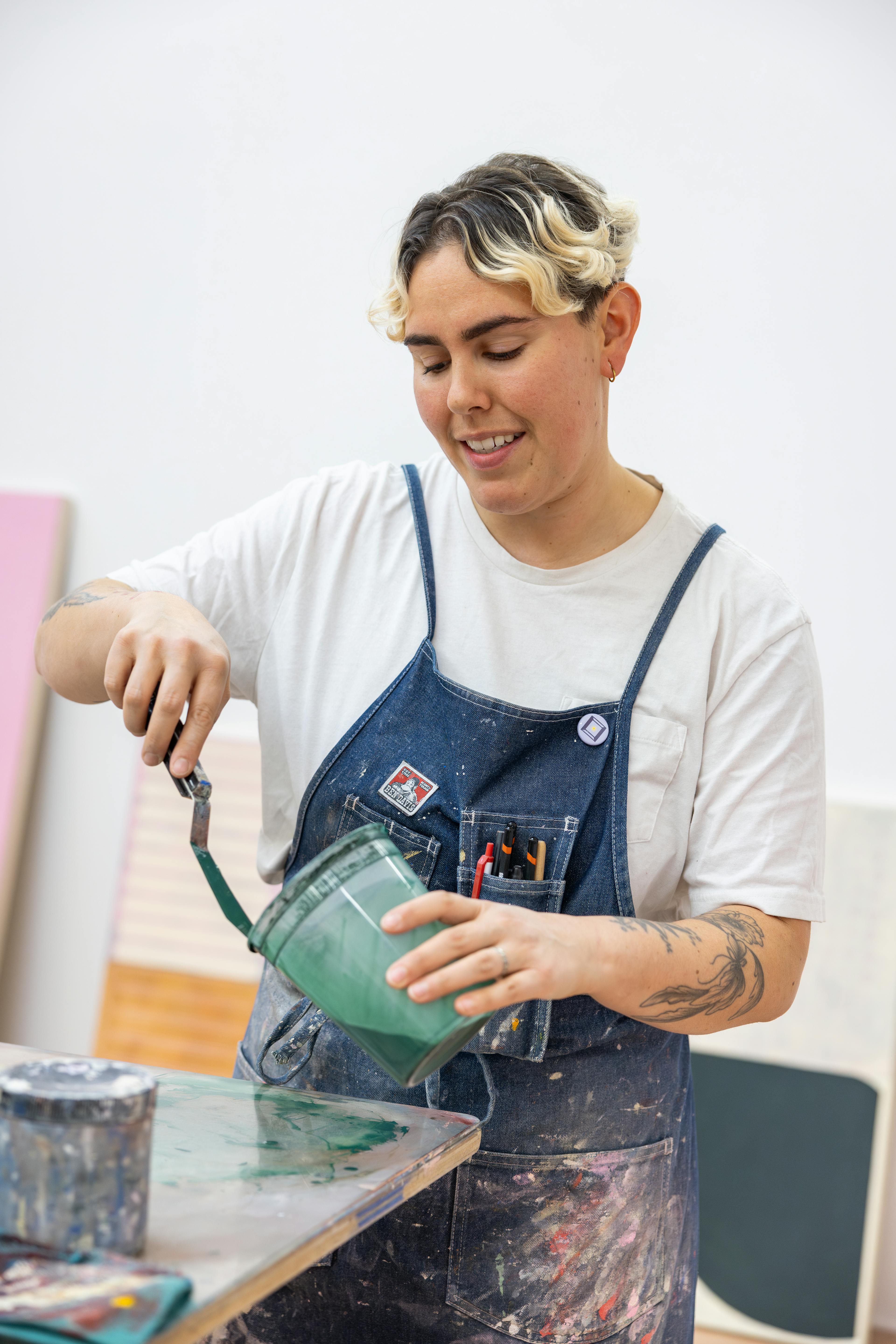 Artist Arielle Zamora preparing a green substrate in a plastic container.