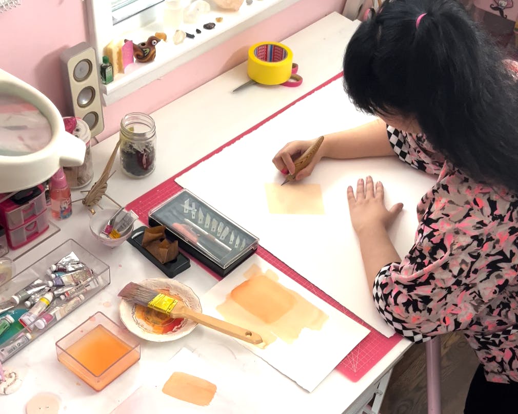 Artist Lucha Rodríguez working in her studio on a knife-cut composition.