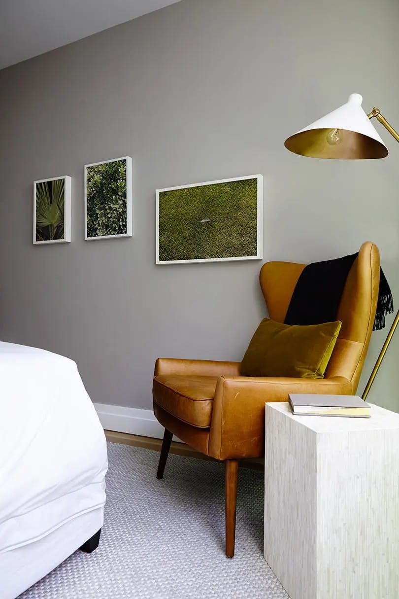 Three photographs of grass and plants by Ryan James MacFarland on a bedroom's light gray wall.