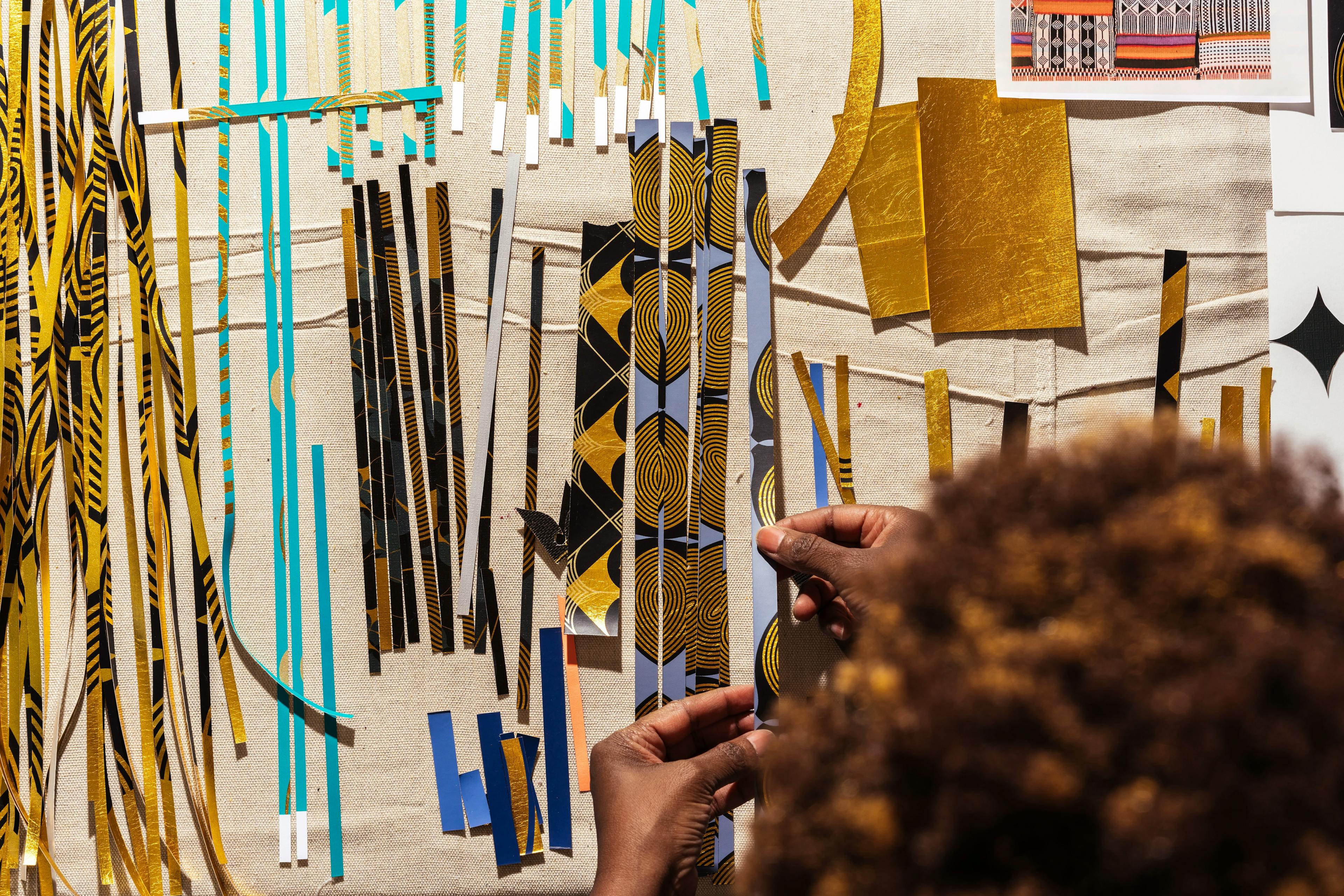 Artist Lisa Hunt with strips of collaged material on a table during her artist residency at MacArthur Place.