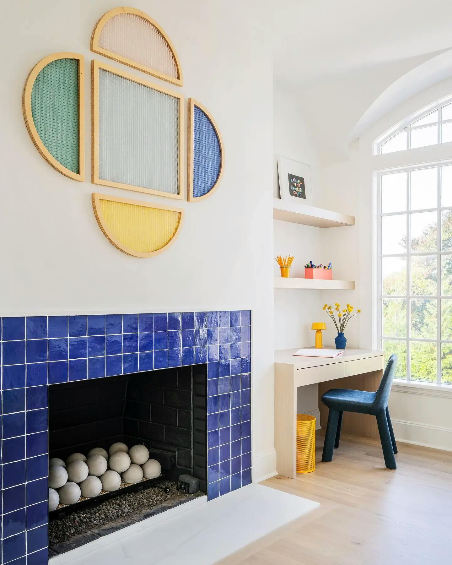 Stitched shaped screens in the shape of a clover by artist Hayley Sheldon above a blue-tiled fireplace in a children's playroom.