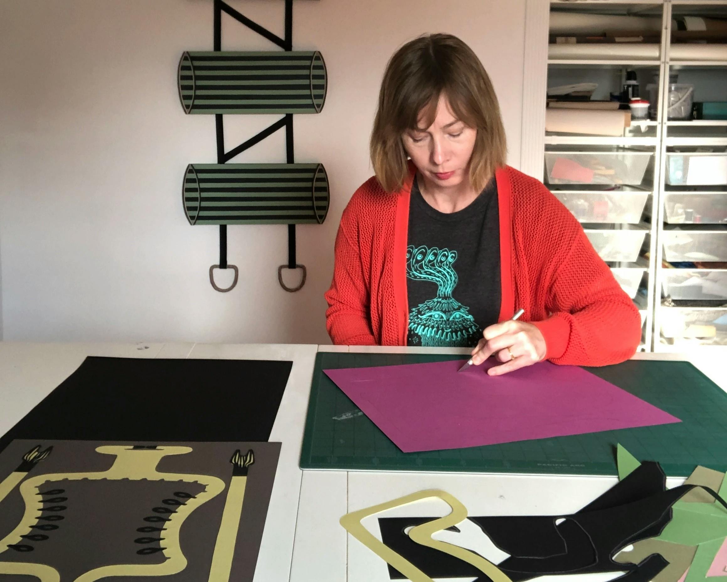 Artist Natalie Beall working on a paper collage in her studio.