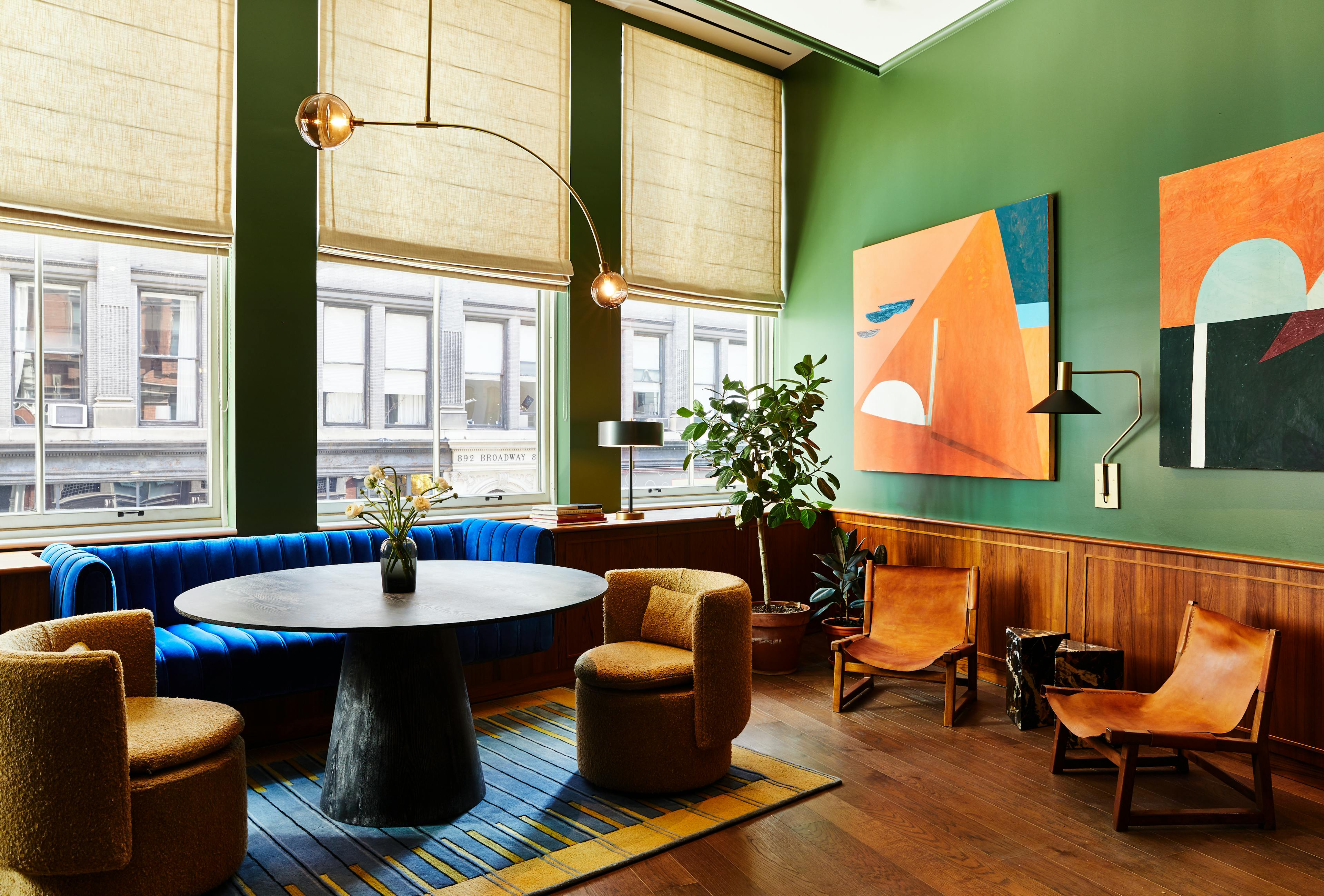 Two abstract, geometric paintings by artist Kristin Texeira installed on a green wall within a lounge area at the Chief Flatiron Clubhouse.