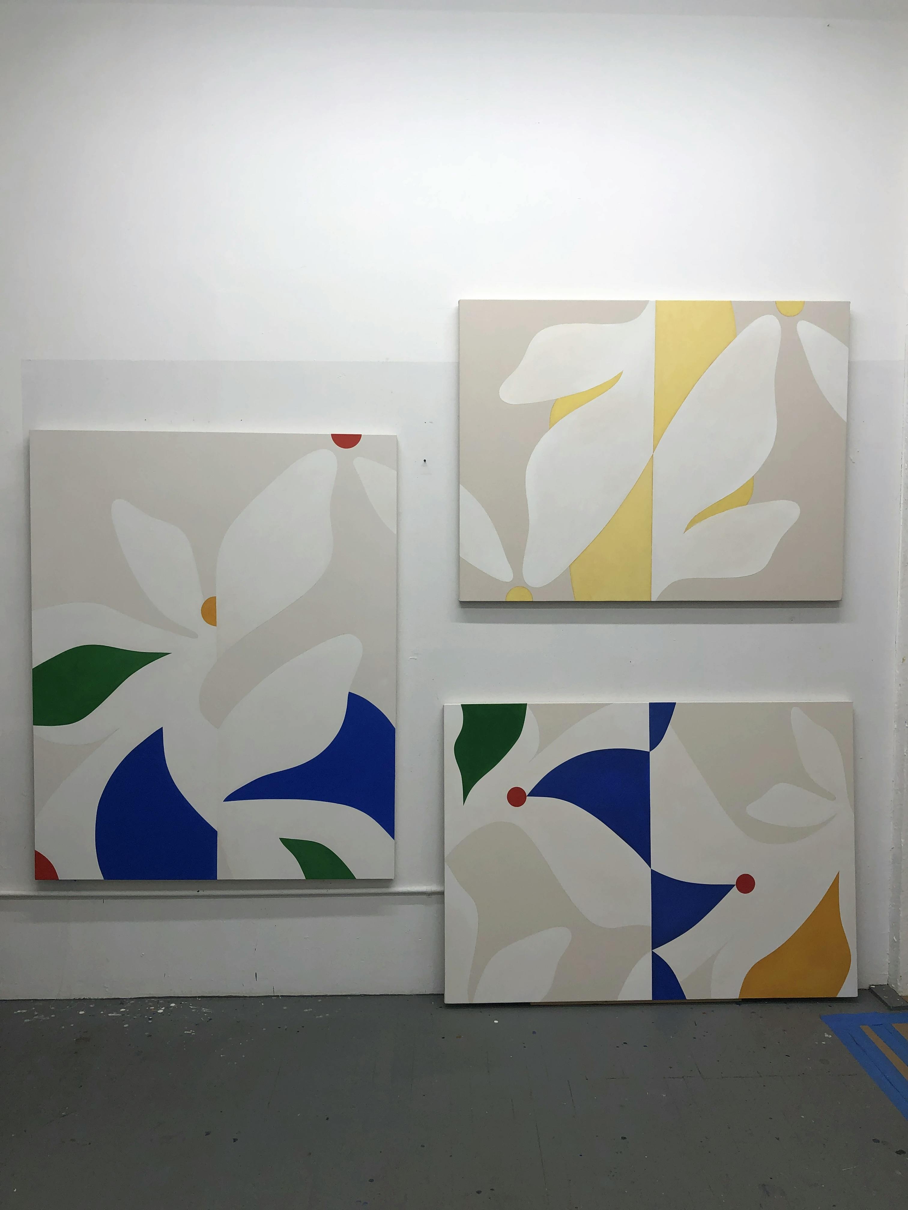 Three abstract botanical paintings on a white wall in artist Senem Oezdogan's studio.