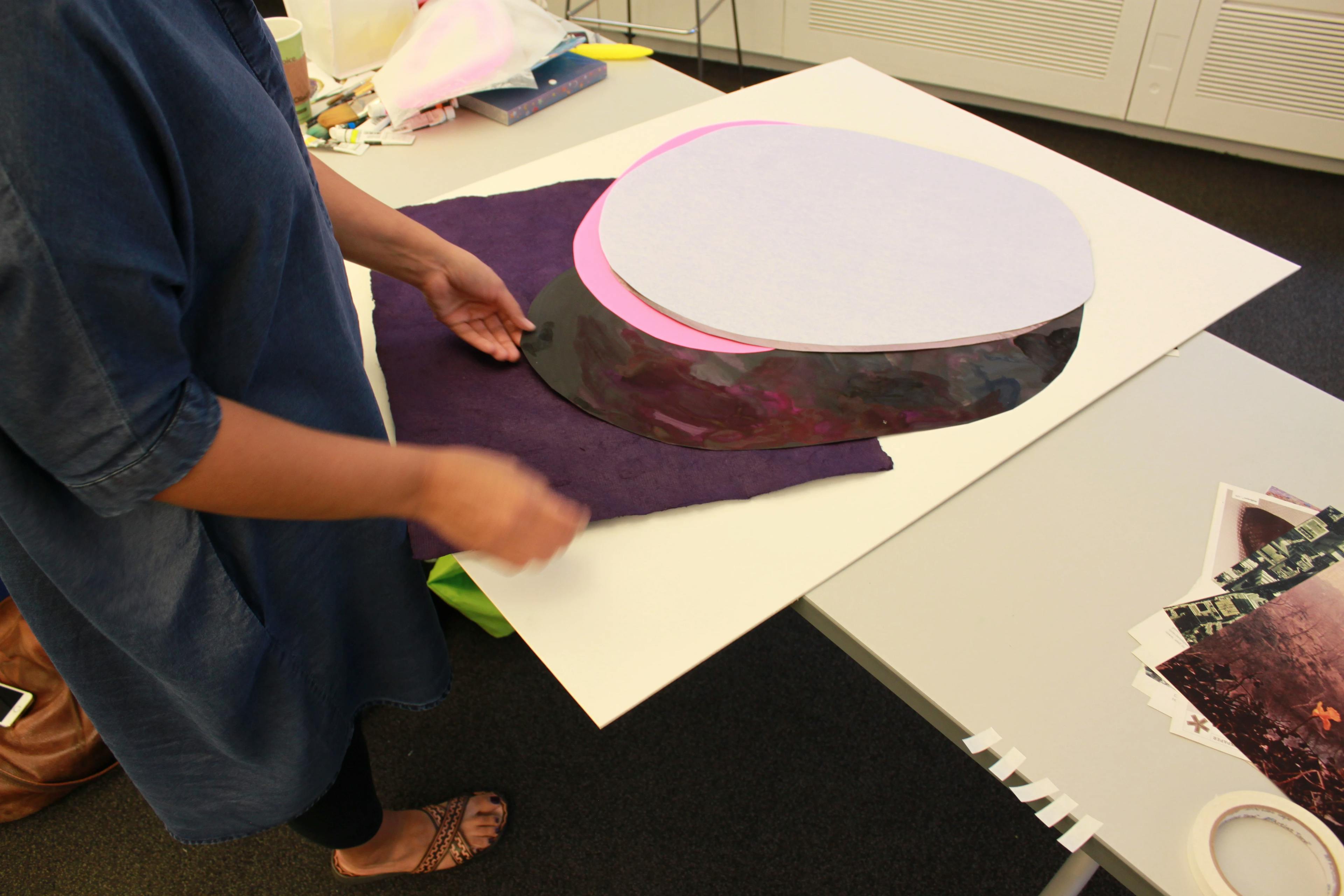 Artist Xochi Solis layering down different purple circles to construct her collage artwork.