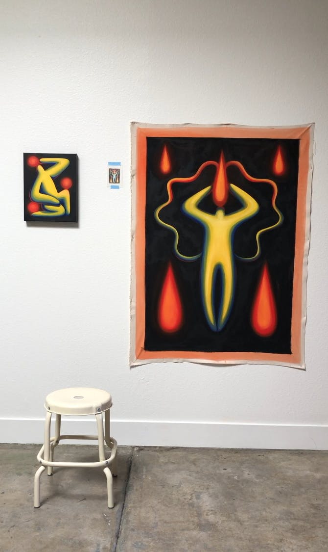 Two paintings of abstract, yellow figures by artist Jocelyn Tsaih installed on a white wall in her studio.