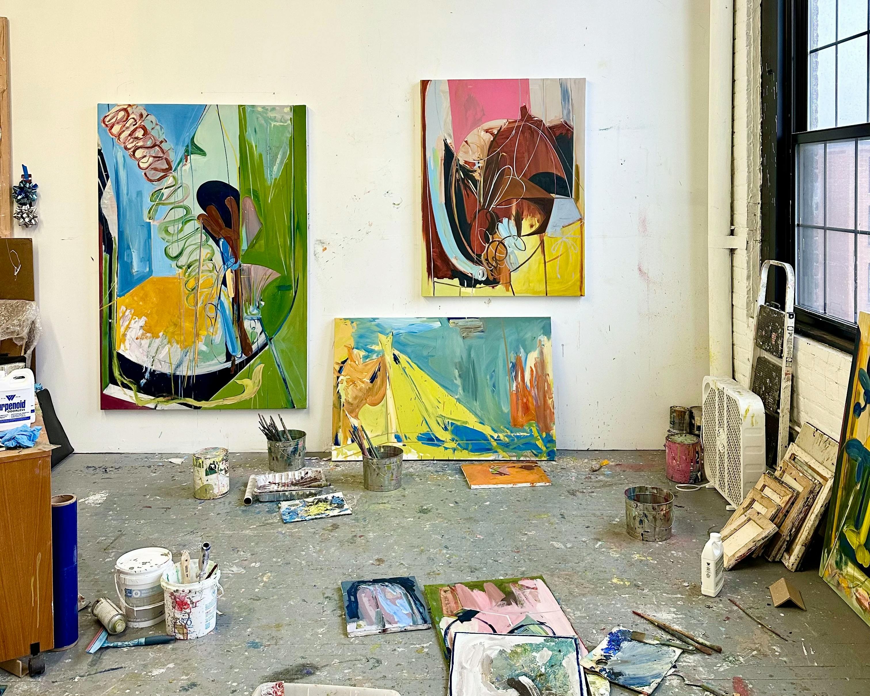 Abstract, colorful paintings installed on a white wall in artist Diana Delgado's studio.