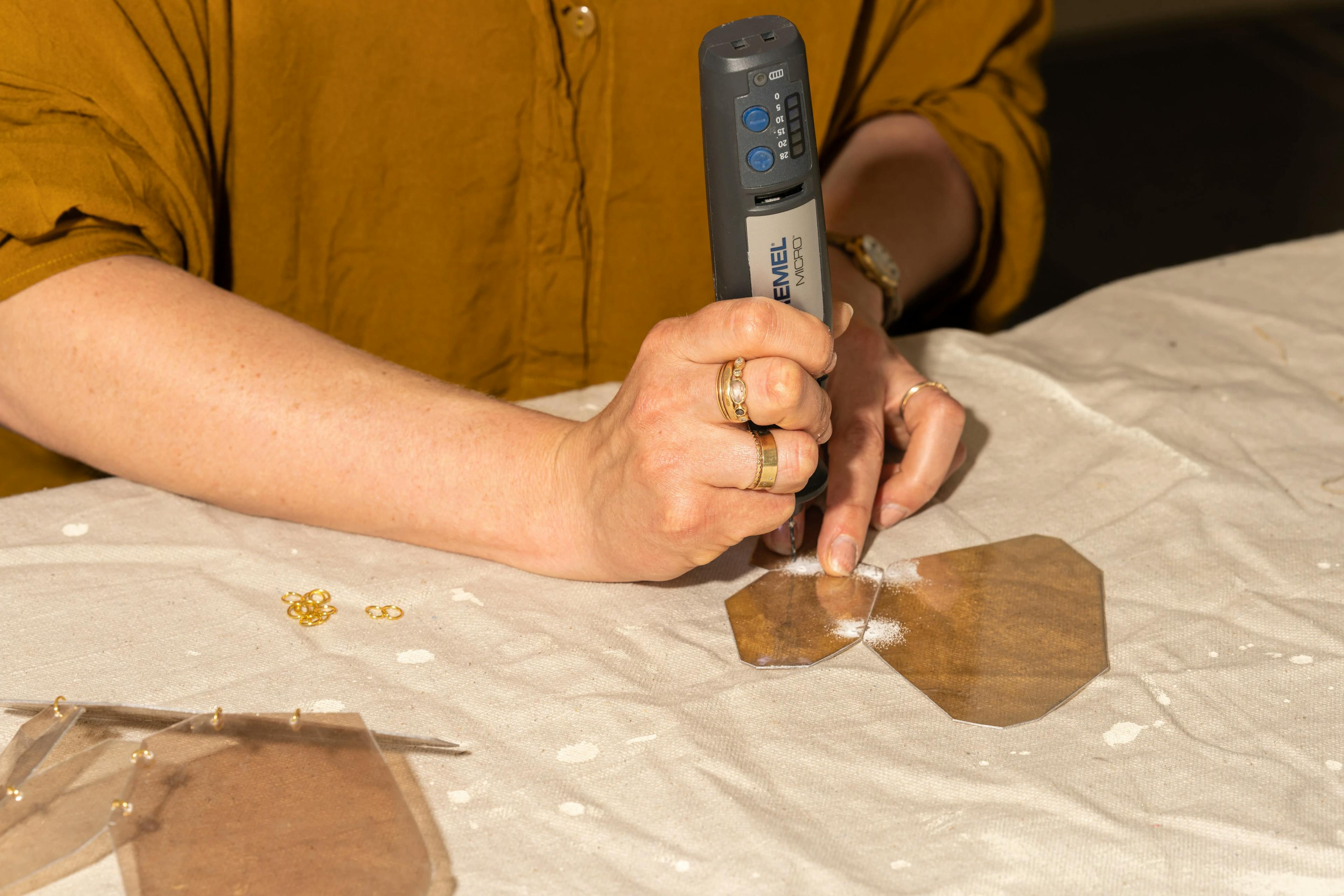 Artist Christina Watka uses a tool to make a hole in a piece of mica at MacArthur Place.