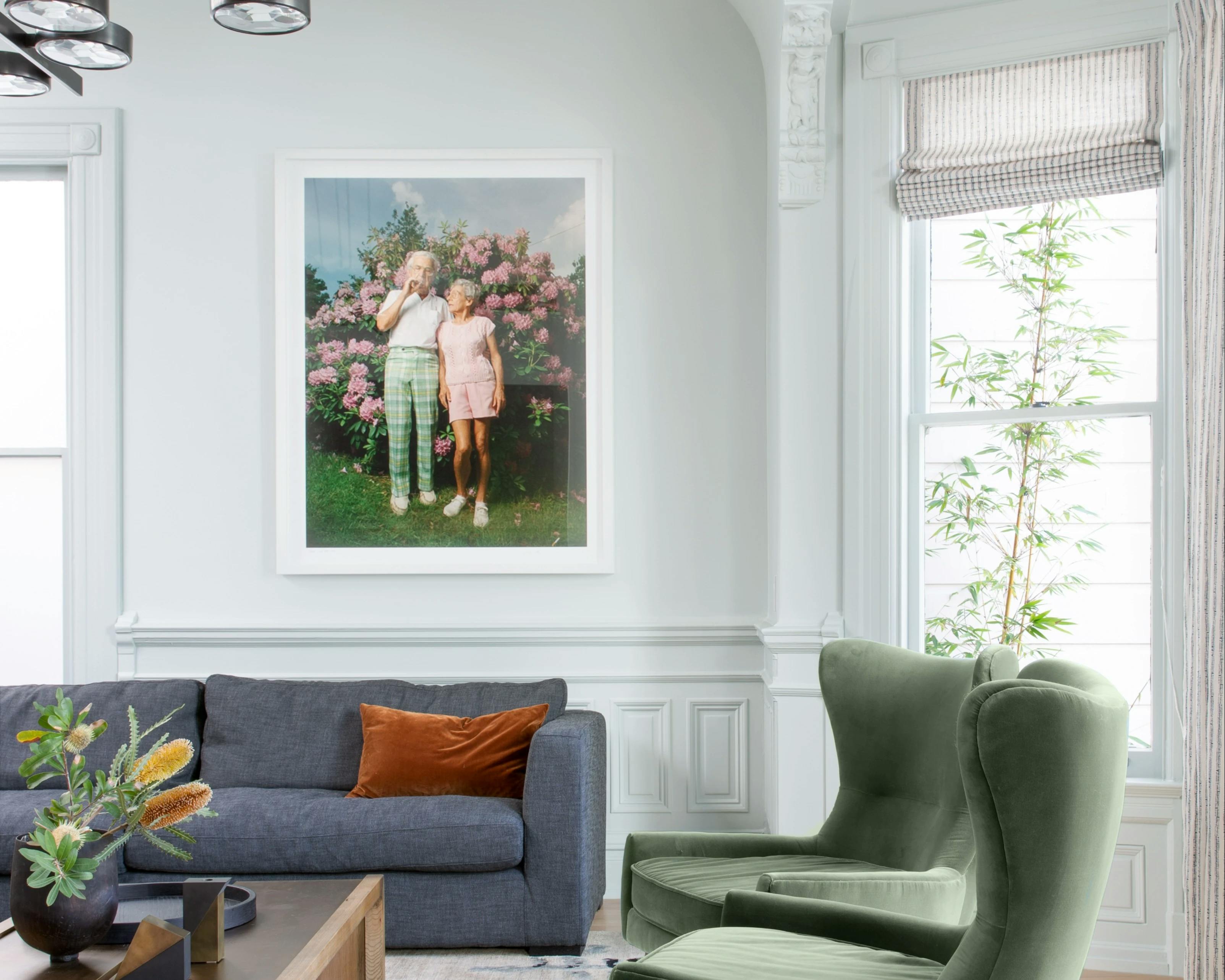 A framed photograph of an elderly couple smoking a cigarette by artist Michael Northrup installed on a white wall in a Victorian home. 