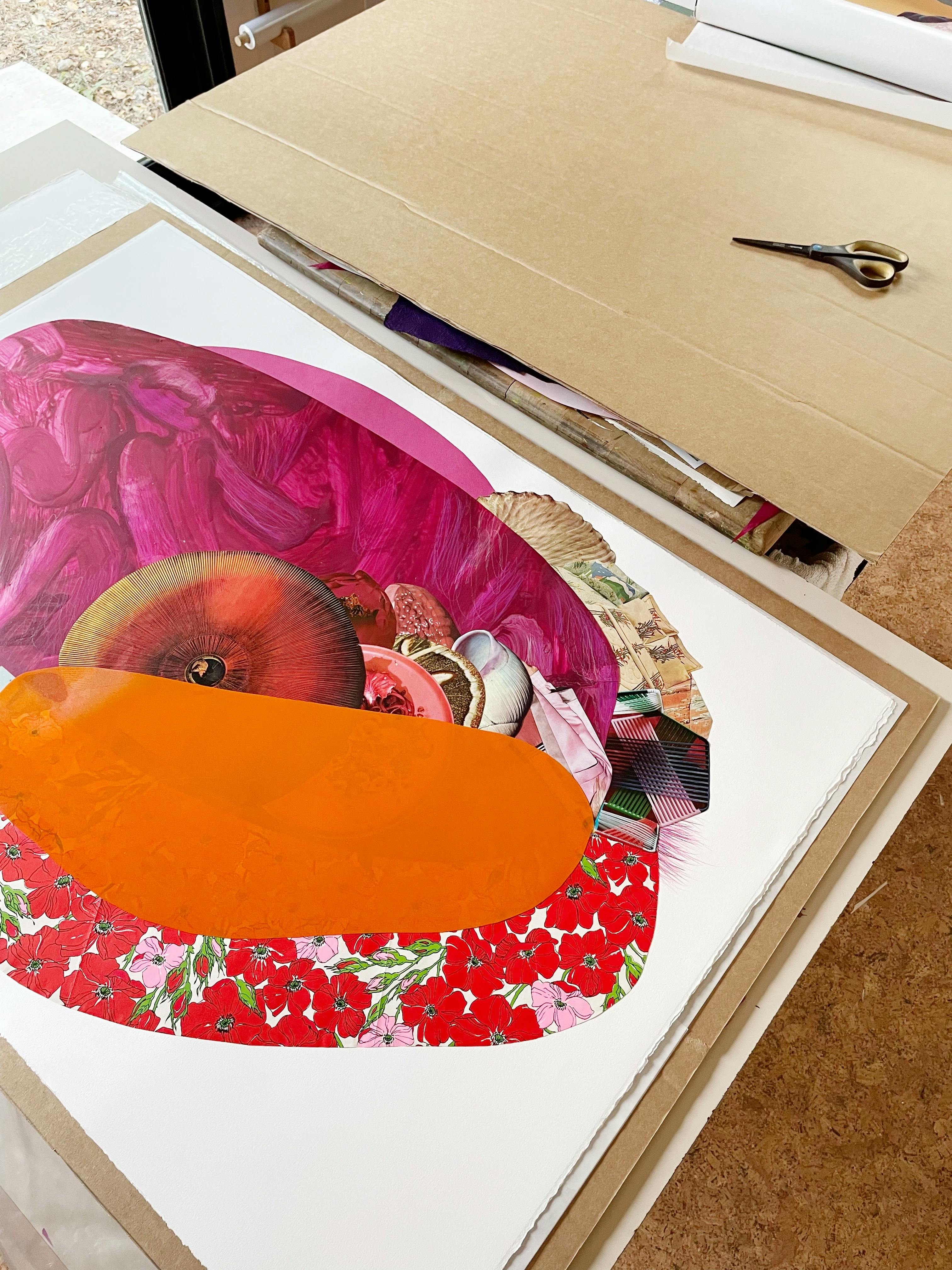 Pink and orange mixed-media collage with flowers by artist Xochi Solis on a piece of cardboard in her studio.