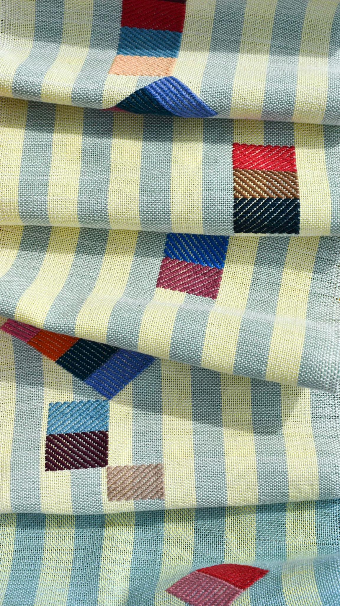 A close-up of blue and yellow striped fabric with folds in it, handwoven by artist Sarah Sullivan Sherrod.