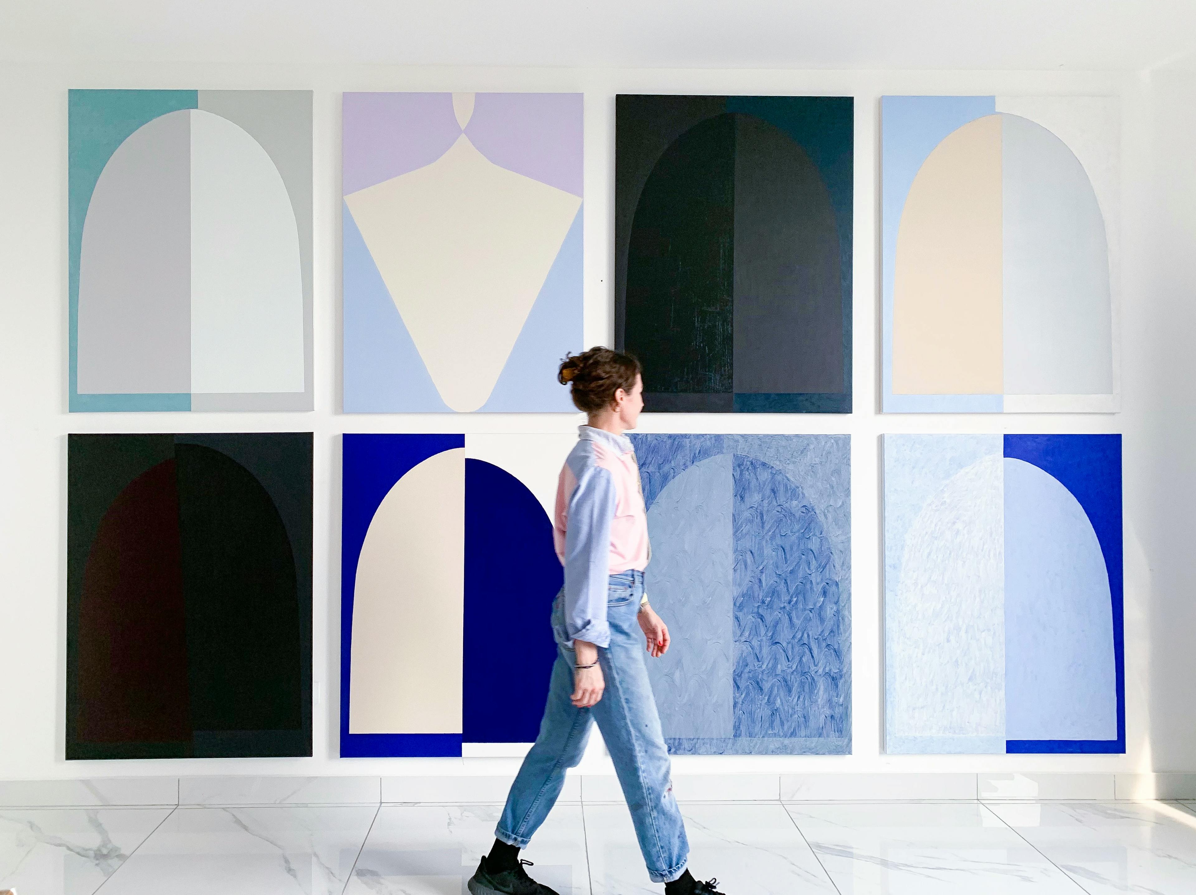 Artist Aschely Vaughan Cone walking in front of her large arch paintings.