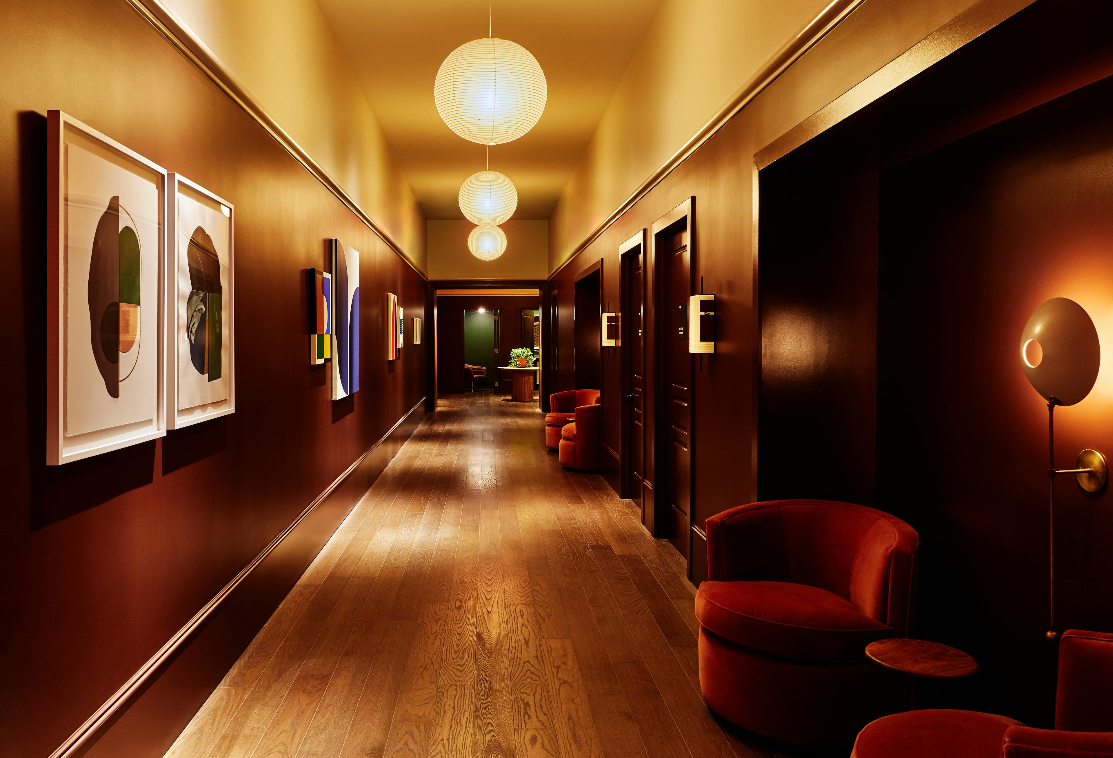 A corridor at the Chief Flatiron Clubhouse with artwork installed on the walls and orb light fixtures installed on the ceiling.