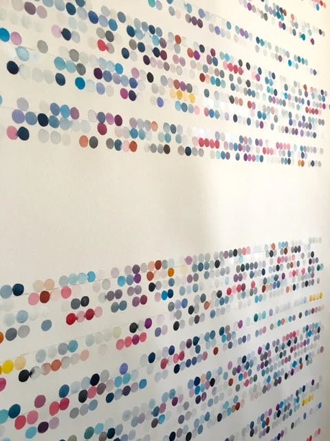 Close-up of color-coded dots translating to text on paper by artist Gail Tarantino.