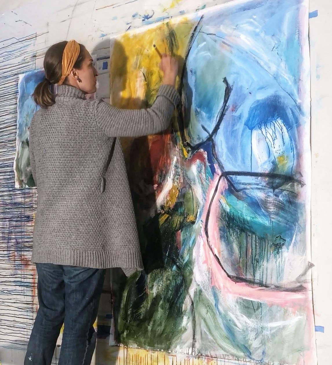 Artist Elisa Gomez standing and painting a large, gestural work in her studio.