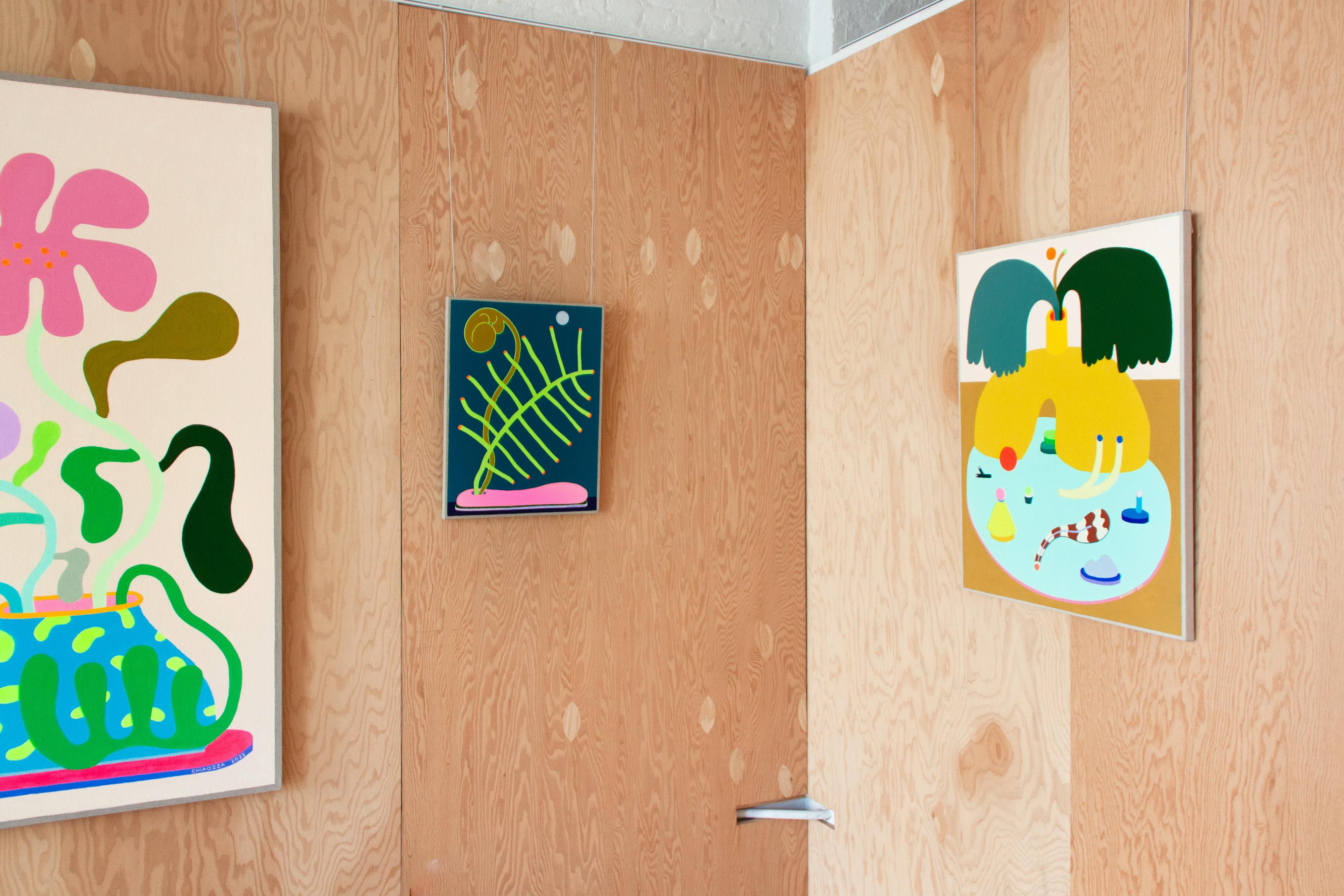 Colorful abstract paintings by Adam Frezza and Terri Chiao, known as CHIAOZZA, hang in a gallery for the exhibition Slow Growth.