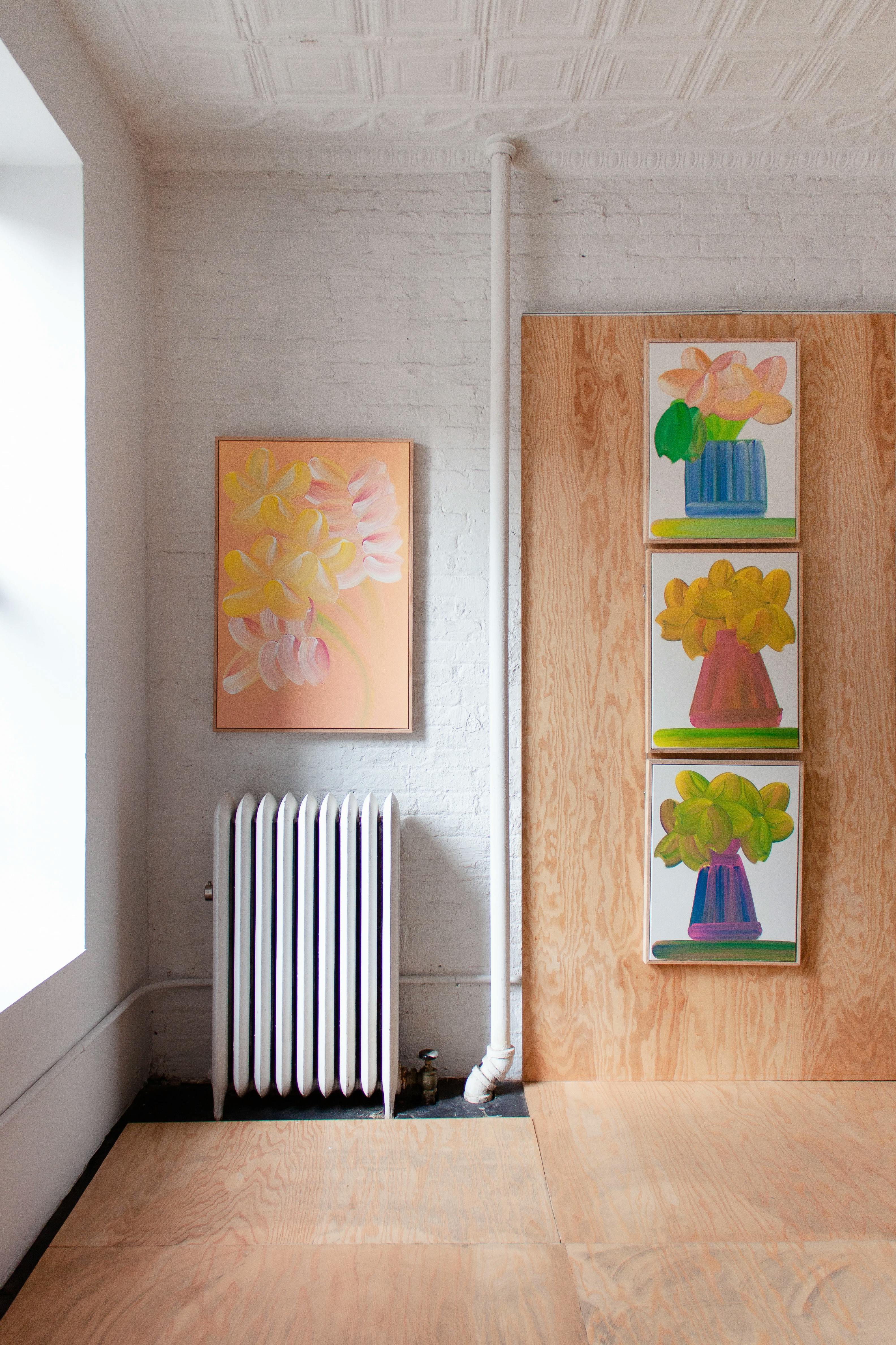 Paintings by Erin D. Garcia, including three vertical depictions of flowers and one abstracted bouquet on a peach background, on wood-clad walls in the exhibition Group 5.