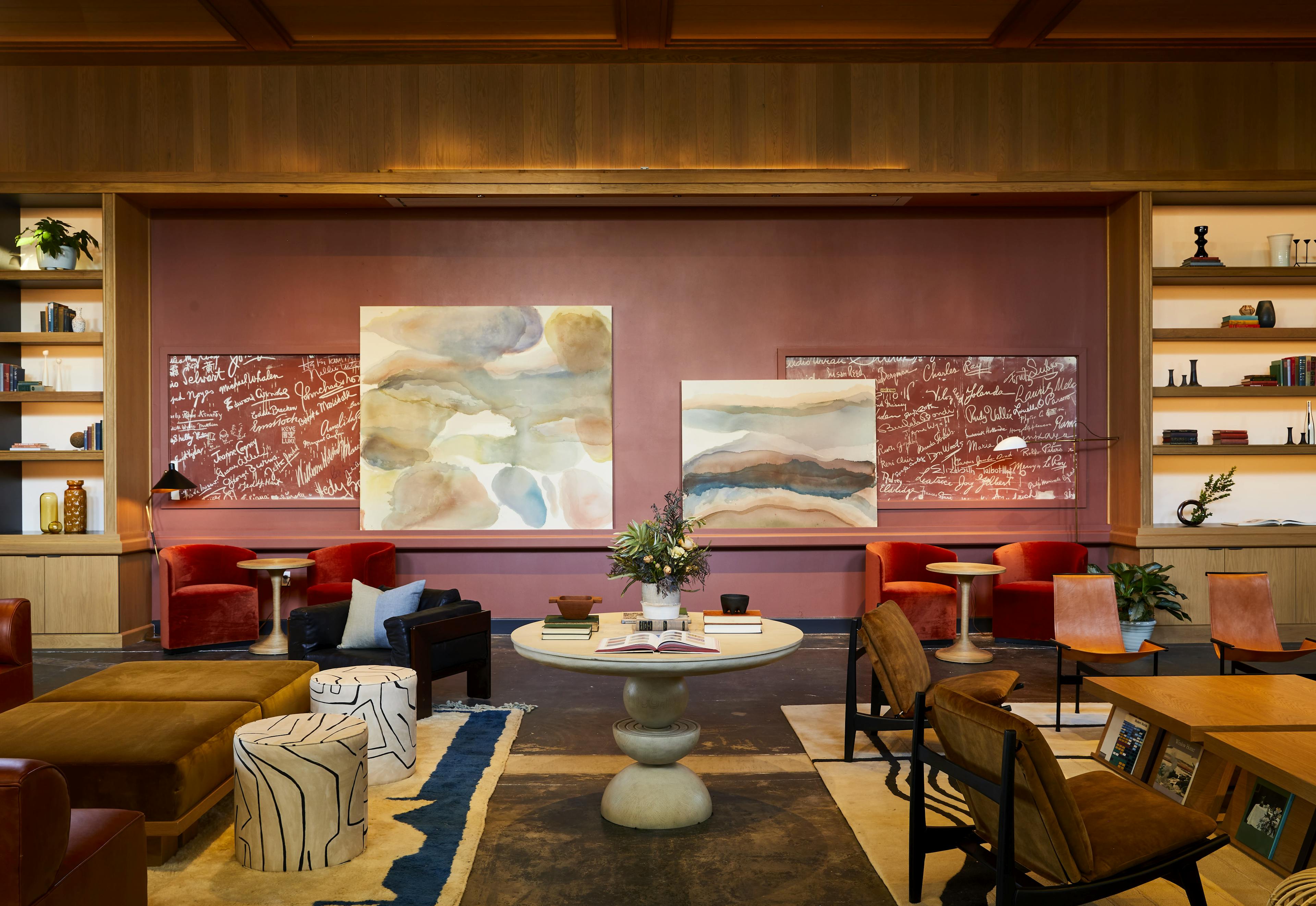 Two acrylic wash paintings by artist Erin Lynn Welsh displayed on a ledge between two bookcases within a lounge area at the Chief Los Angeles Clubhouse.