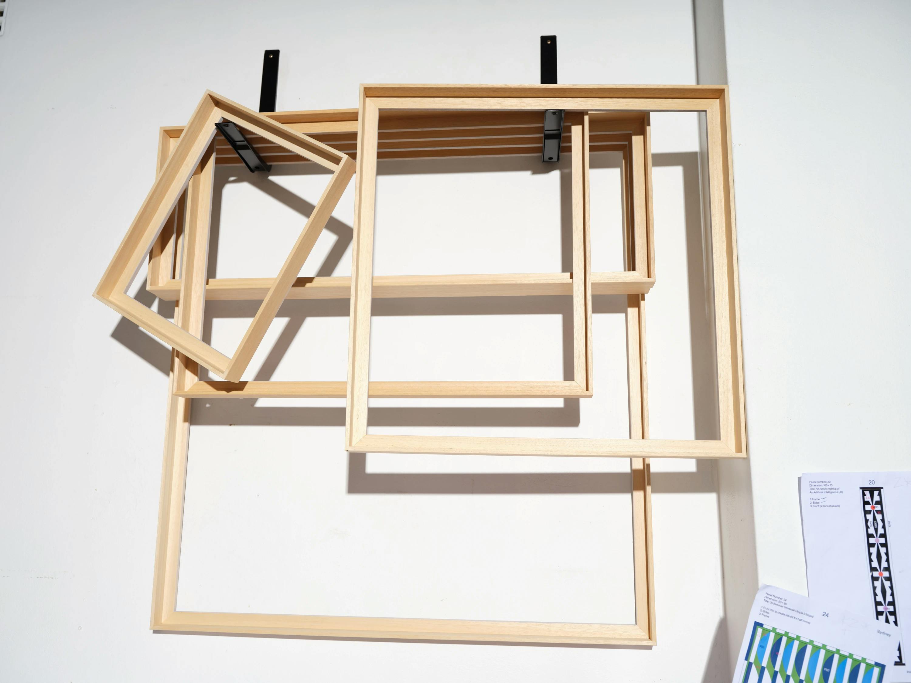 Five unpainted wooden floater frames hanging in Evi O's studio.