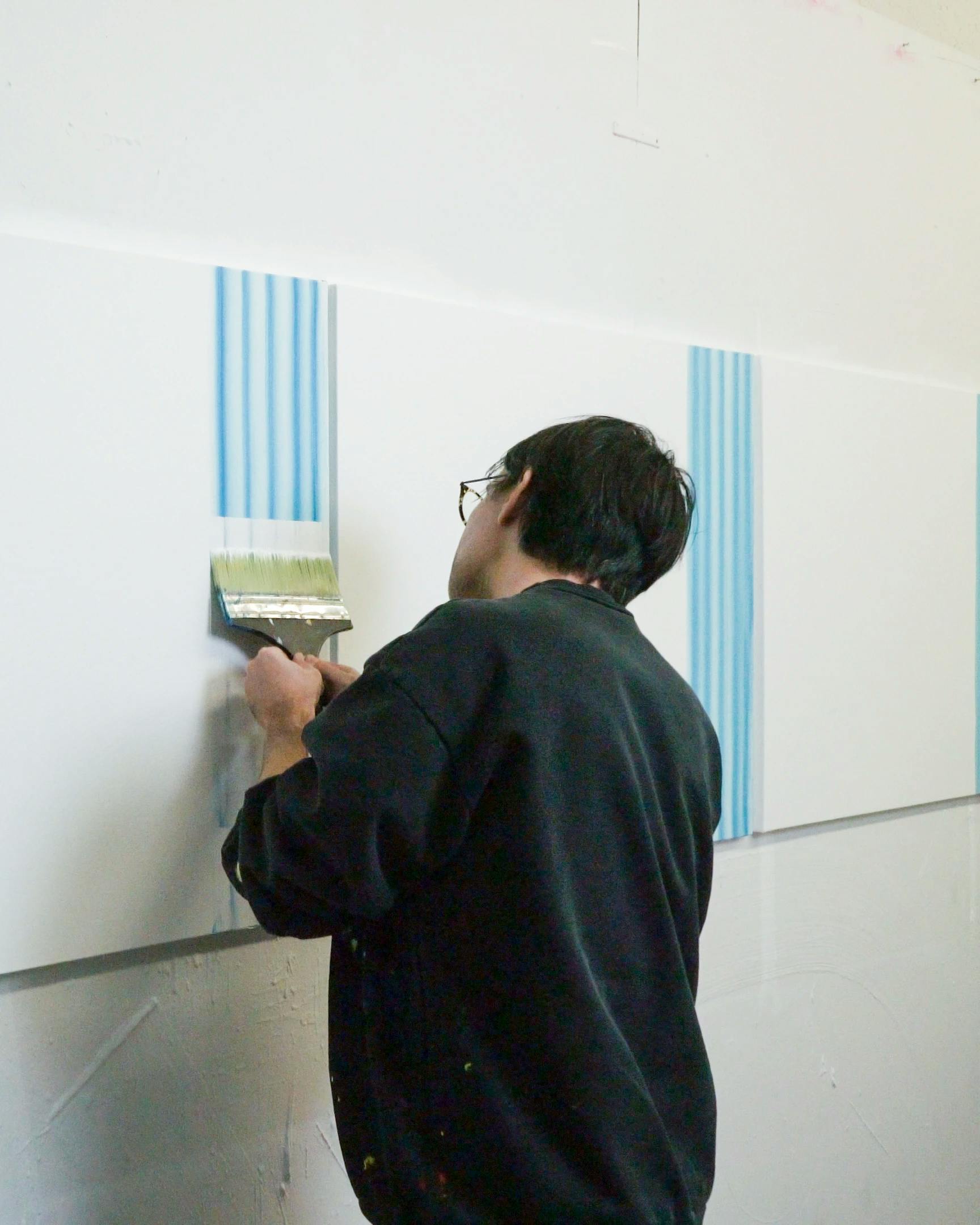 Artist Erin D. Garcia painting stripes on canvas for exhibition Group 5