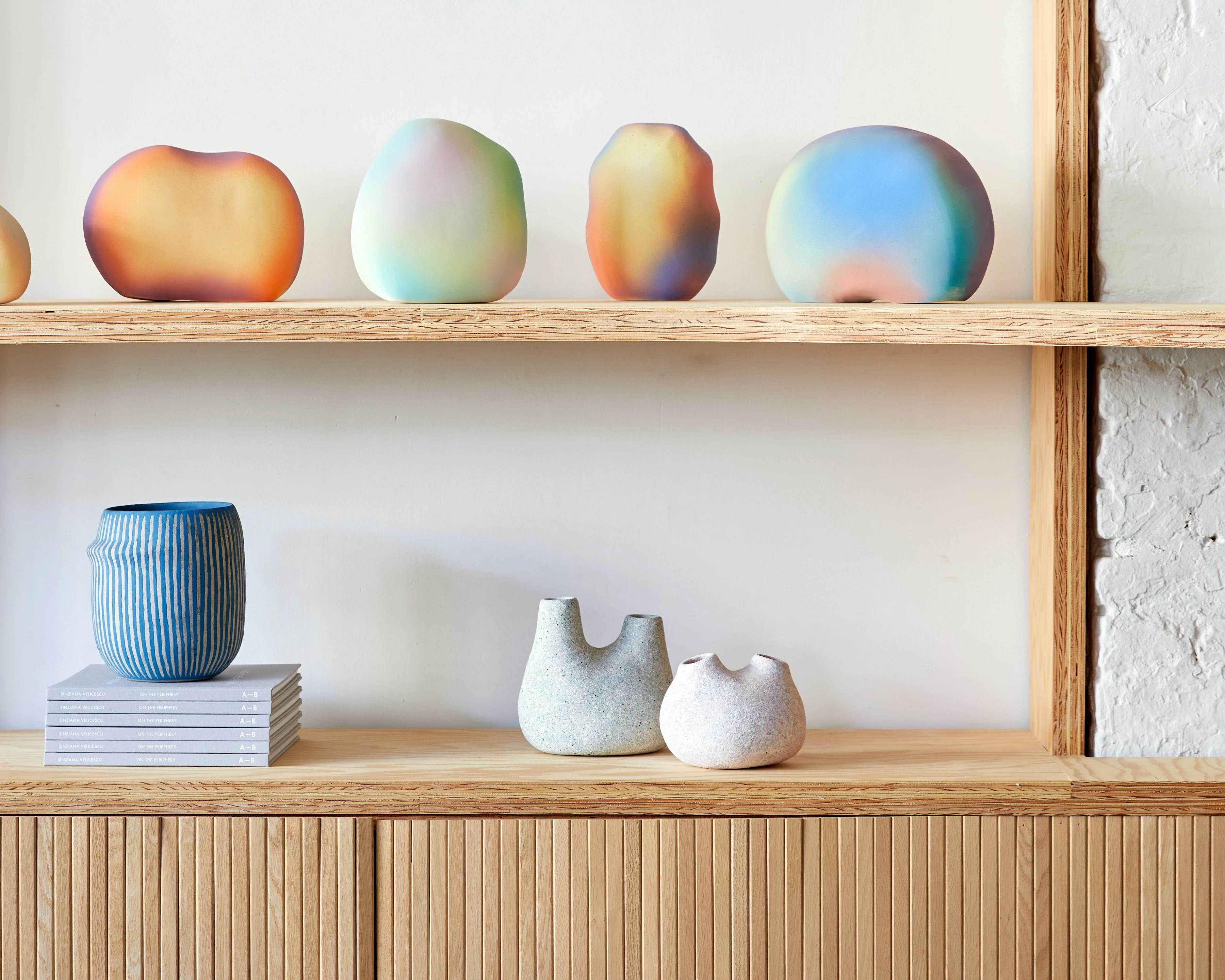 Wooden shelves with four prismatic sculptures by artist Angel Oloshove above three sculptural vessels by Pilar Wiley on display at Uprise Art.
