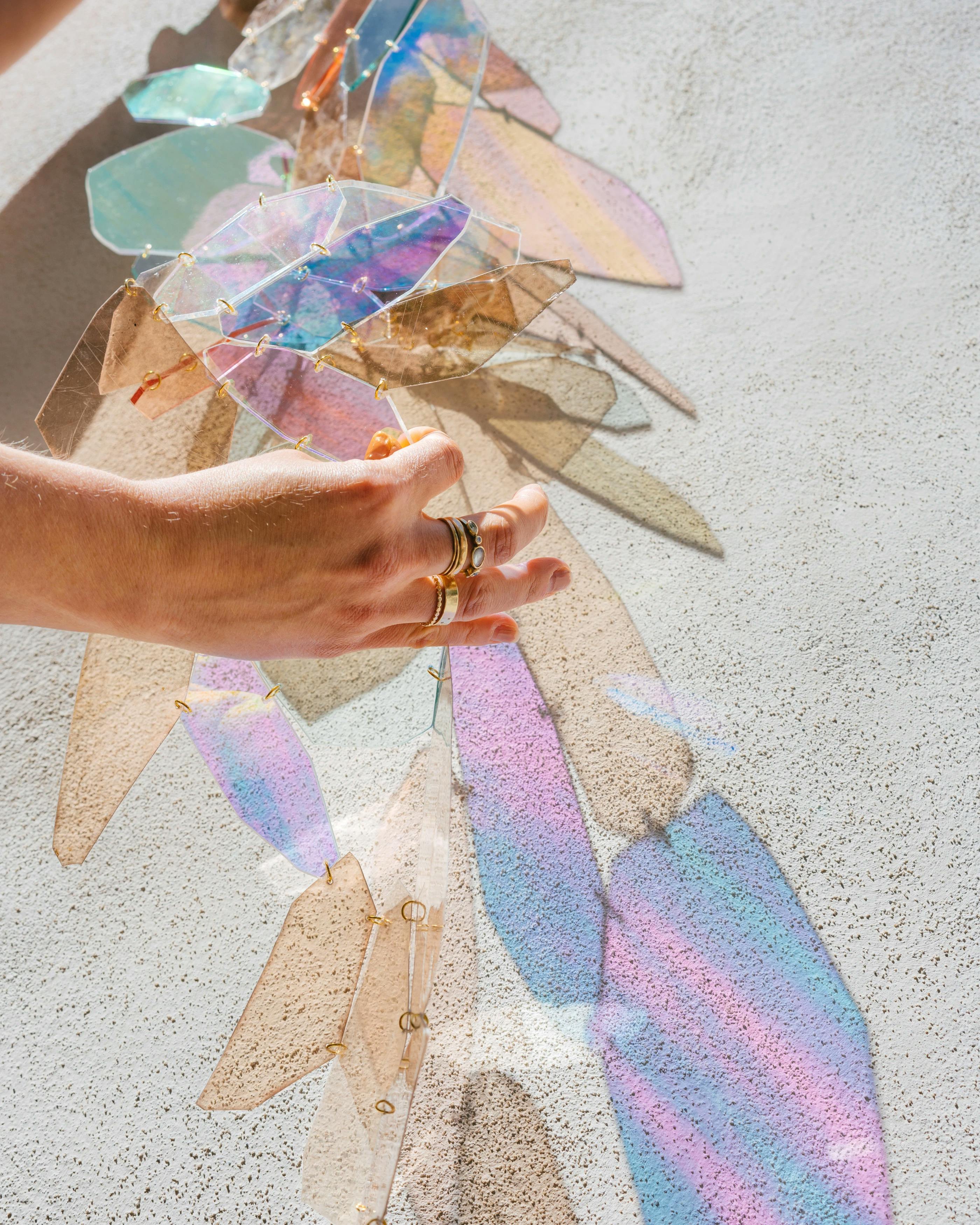 Hand of artist Christina Watka adjusting iridescent sculpture at MacArthur Place.