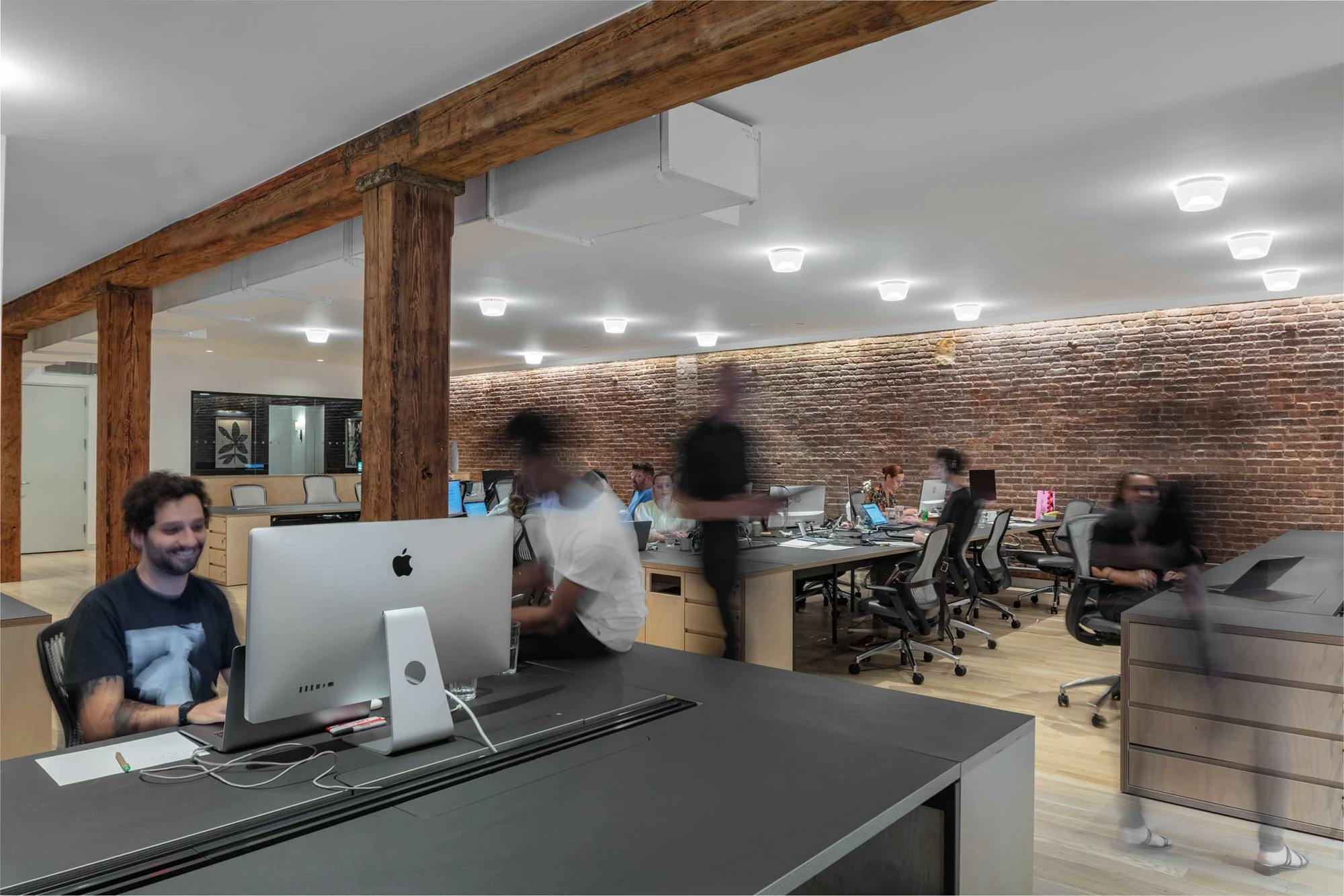 An open-concept workspace at FIG with employees sitting at their desks doing work on their computers.
