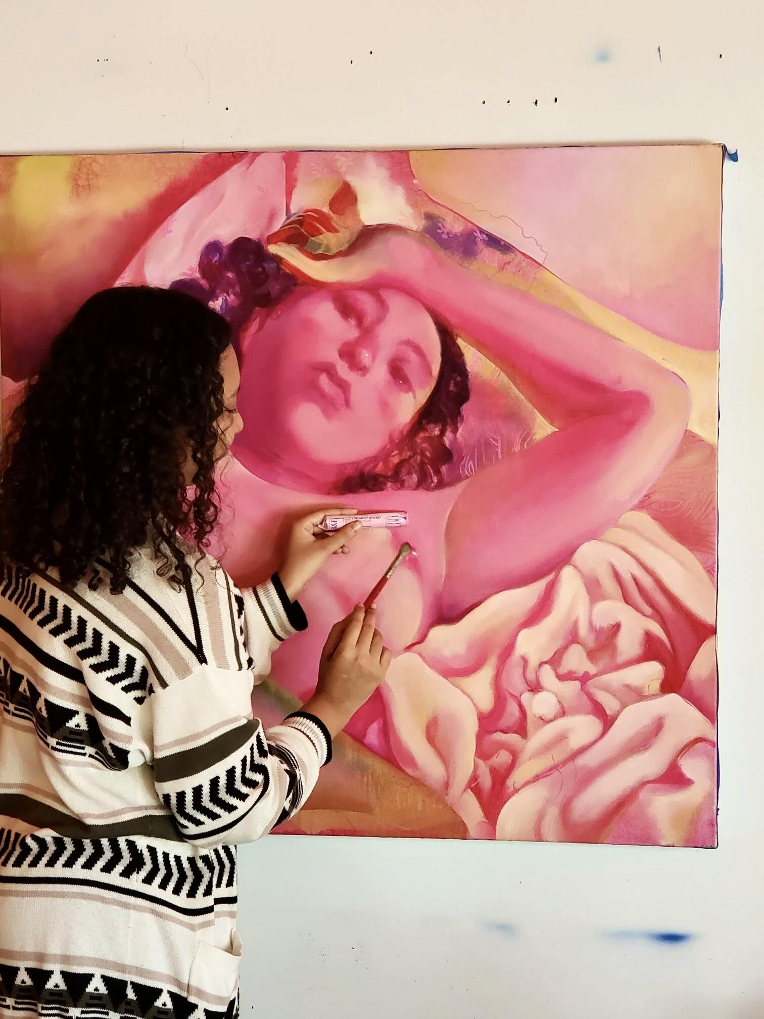 Artist Nefertiti Jenkins in her studio painting a pink female nude.