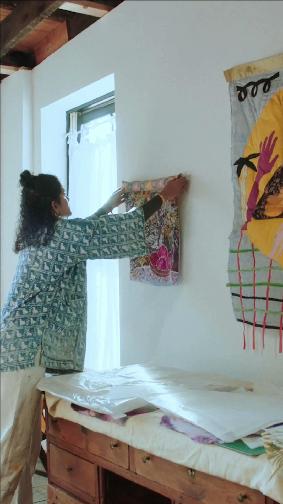 Padma Rajendran hanging up a textile work in her studio. 