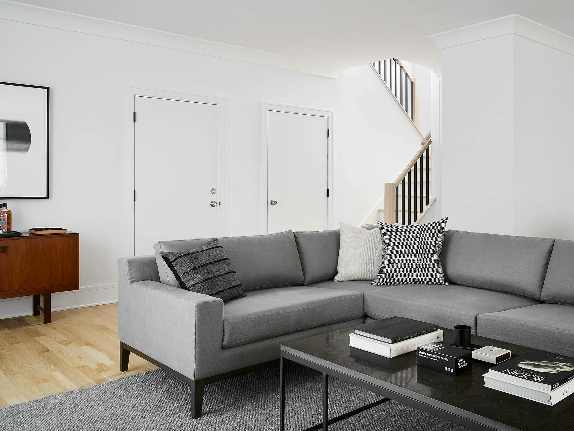 A minimalist living room with stark white walls and a gray sectional sofa in a Chicago apartment.