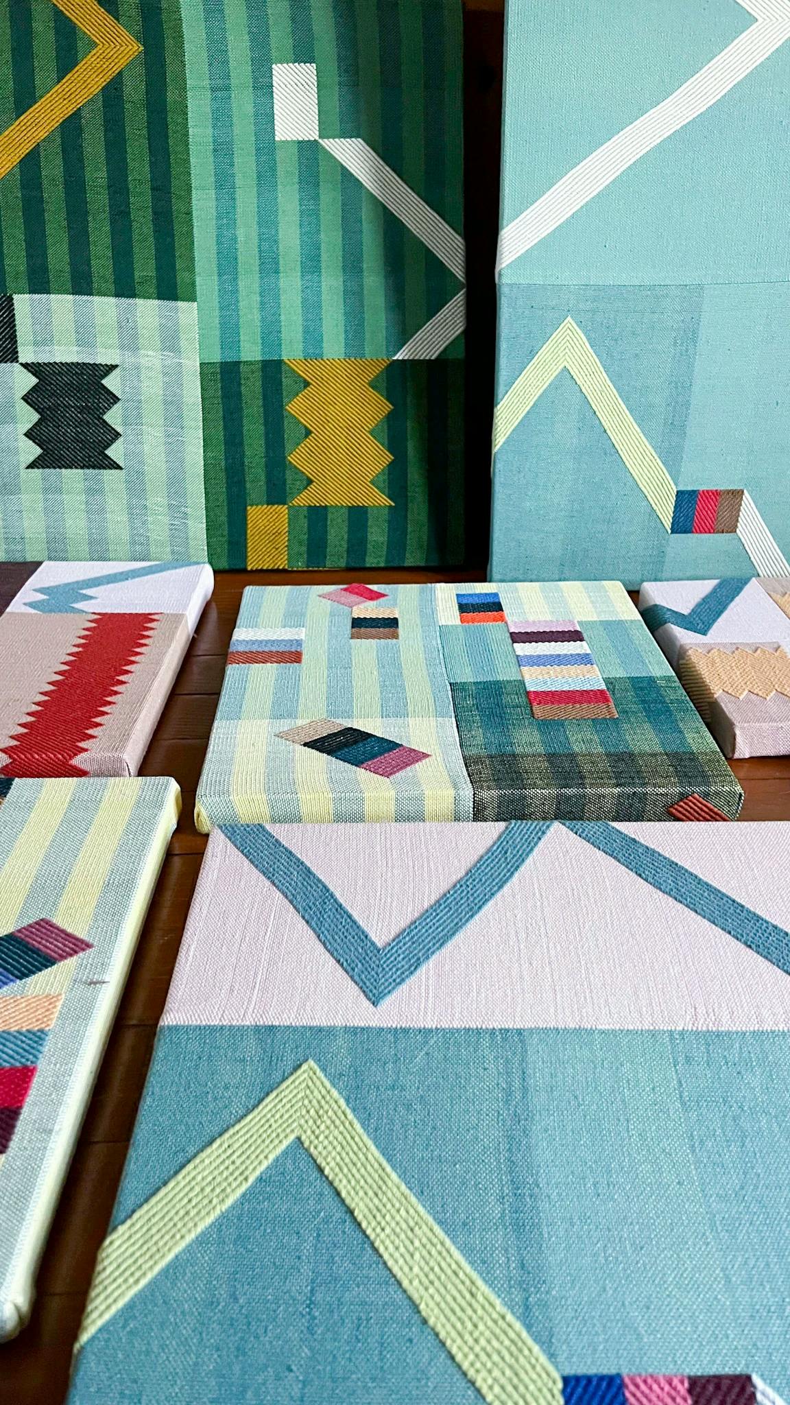 Colorful woven and painted pieces, in various sizes, by artist Sarah Sullivan Sherrod laid out in her studio.