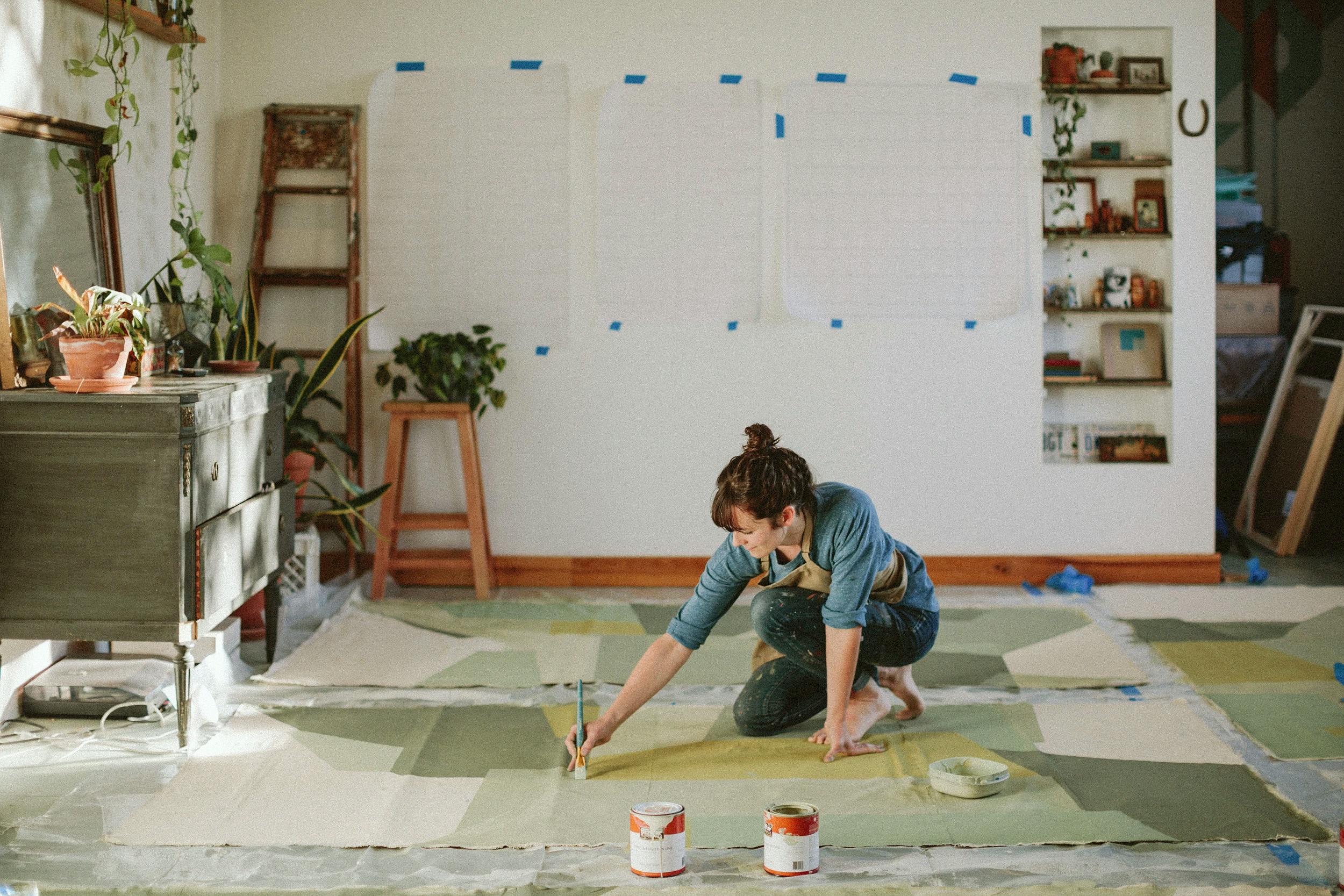 Artist Carla Weeks painting a large green work on canvas in her studio.