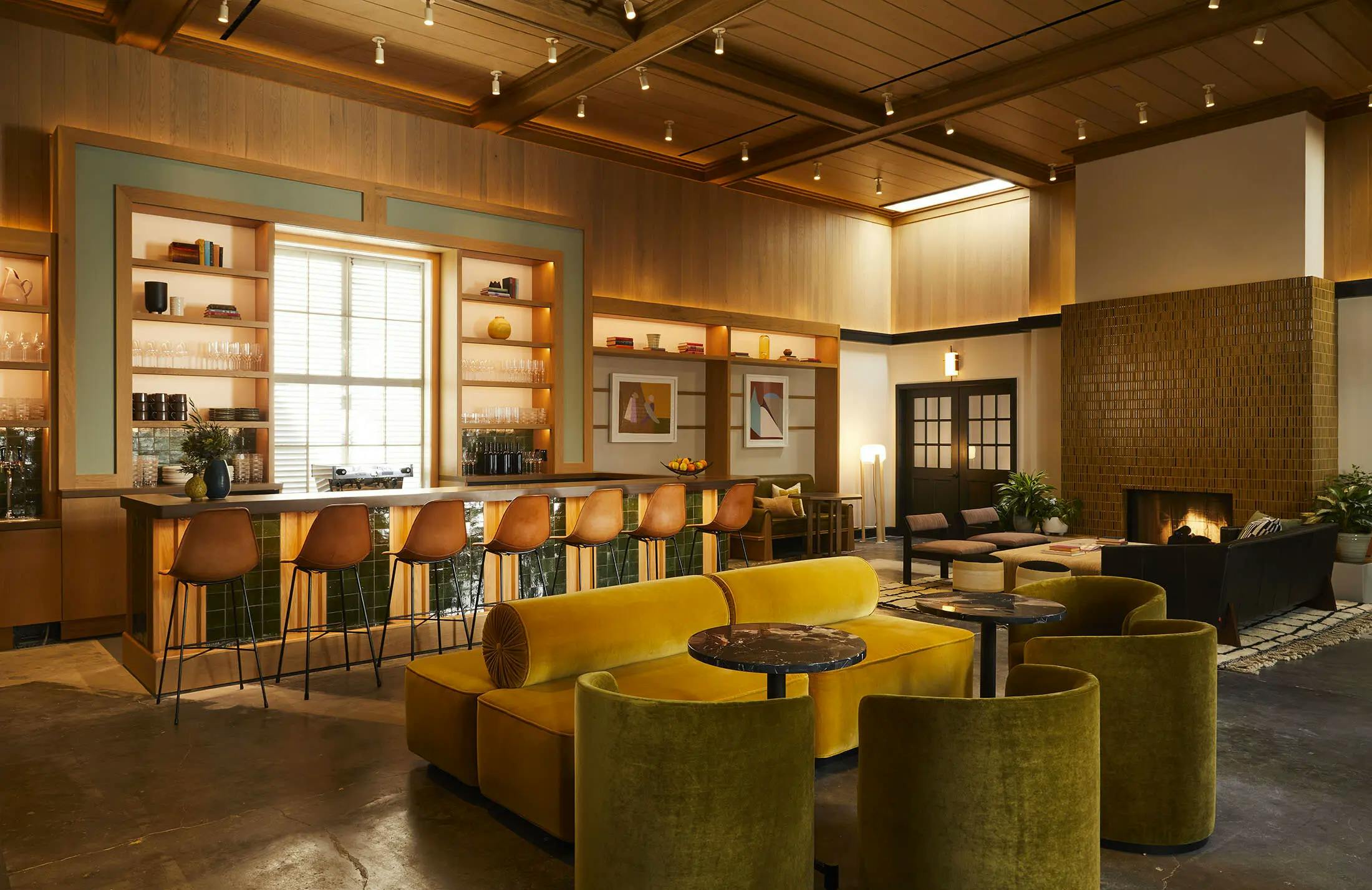 A bar within a lounge area at the Chief Los Angeles Clubhouse with an assortment of velvet chairs and sofas.