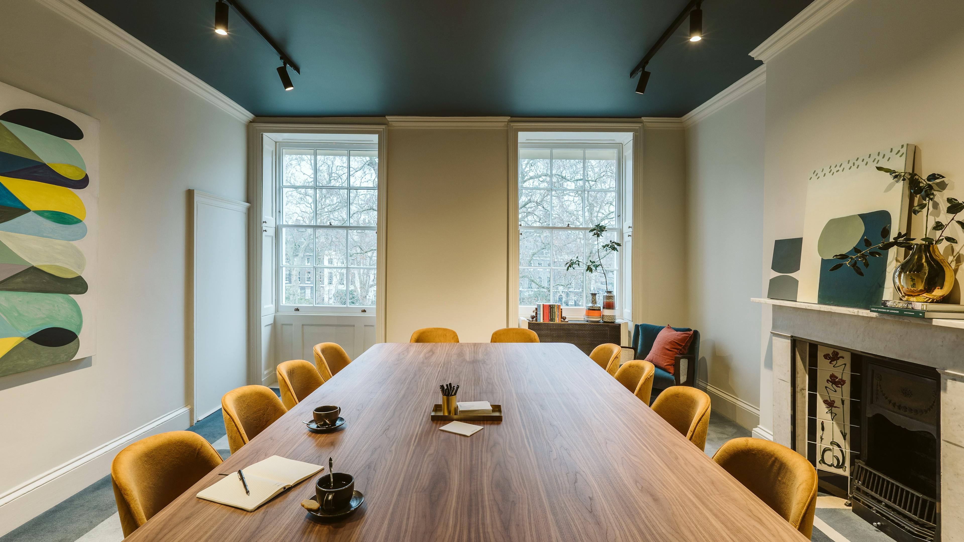 A conference room at Chief London with a long table and original paintings by artists Jackie Meier, Hyun Jung Ahn and Bo Kim.