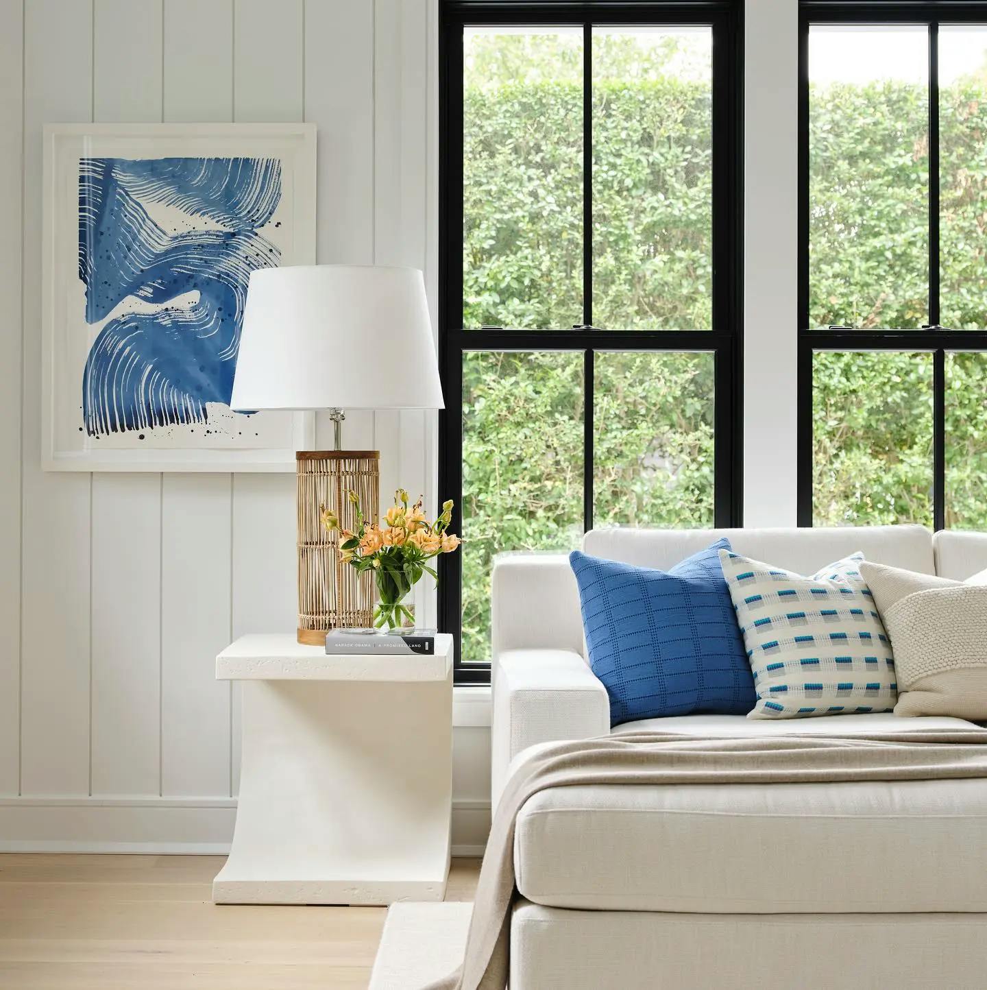A blue, gestural brushwork painting by artist Linda Colletta on a shiplap wall in a white living room. 