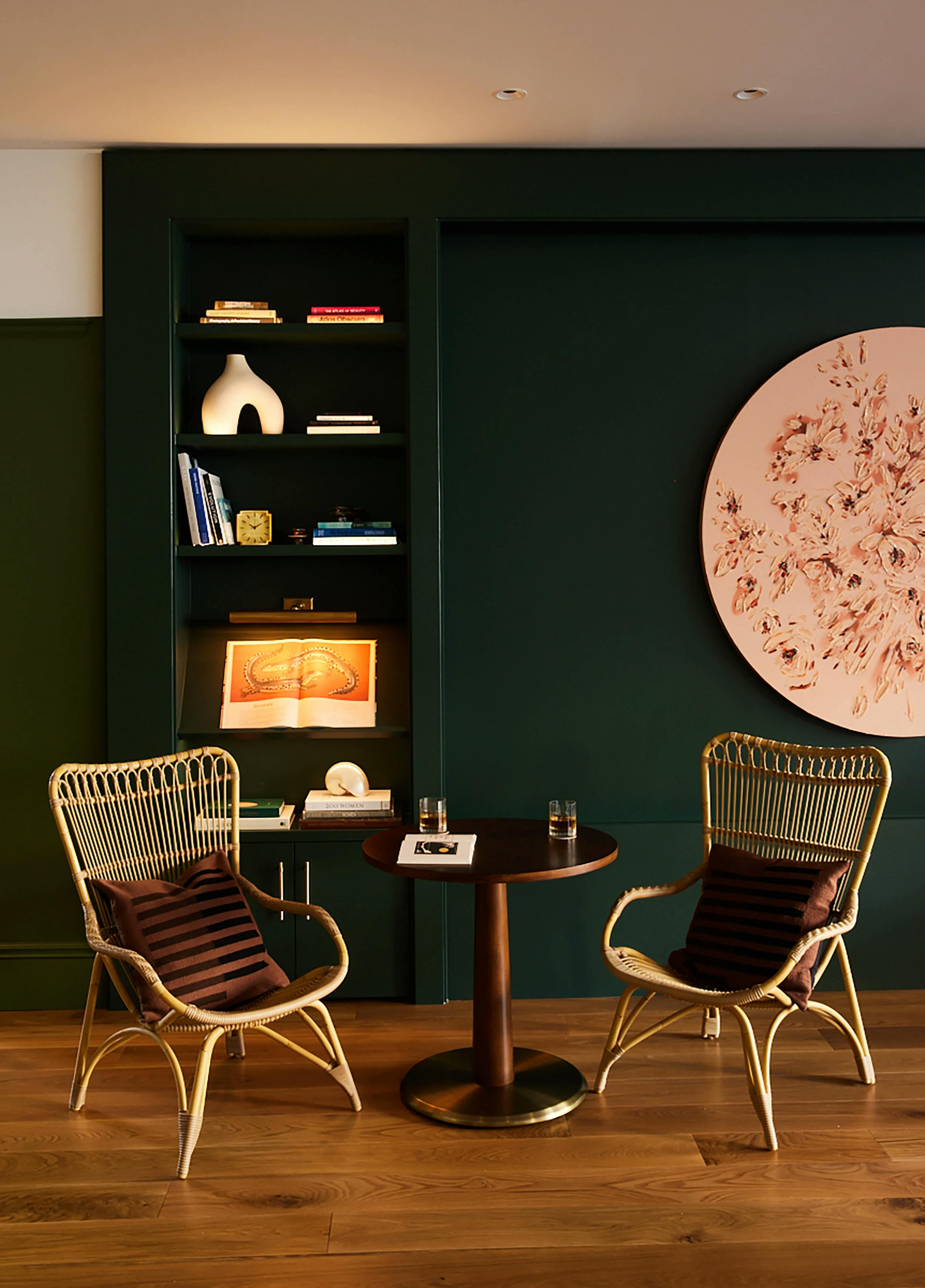 A circular painting with pink flowers by artist Erin Lynn Welsh installed on a dark green wall in the Chief San Francisco clubhouse.