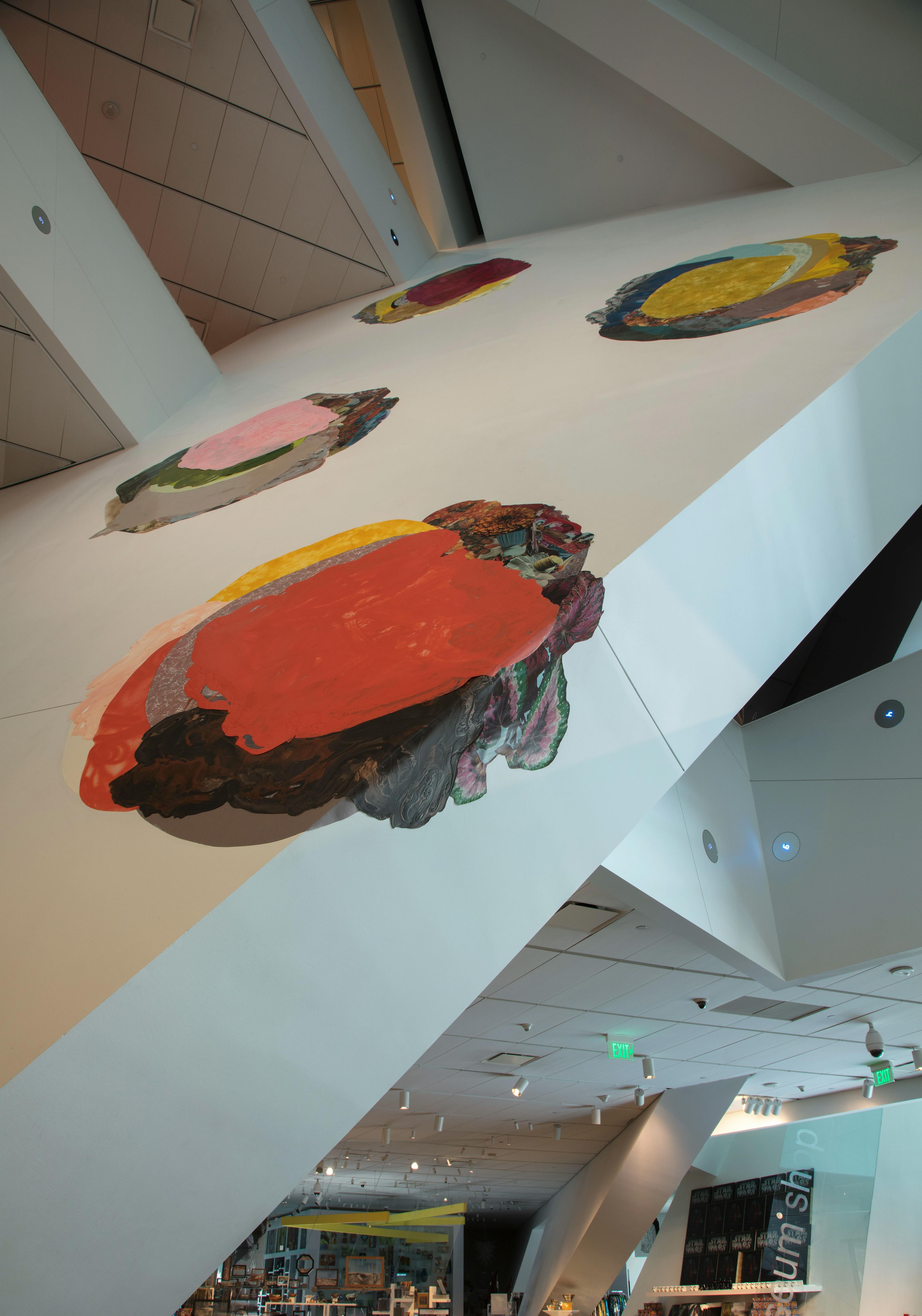 Four mixed-media collages by artist Xochi Solis installed on a slanted white wall in the Denver Museum of Art.
