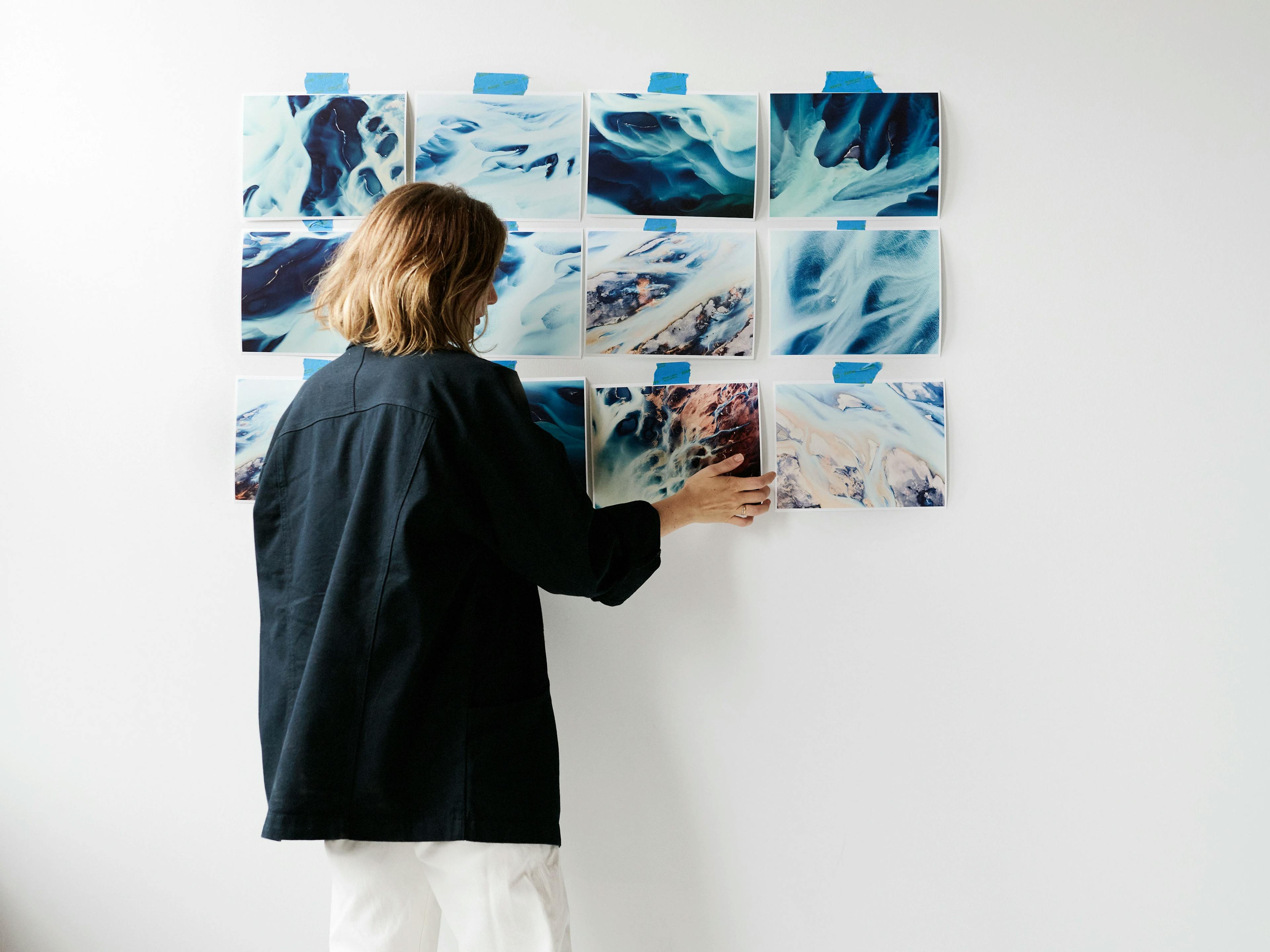 Artist Brooke Holm arranging proofs of her new photographic series on the wall of her studio. 