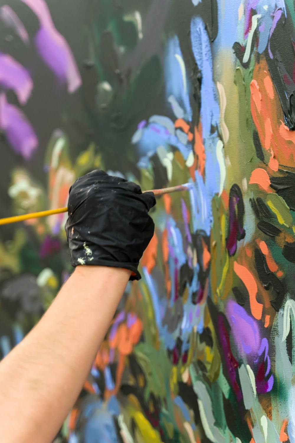 Artist Erin Lynn Welsh working on a blue, orange, purple and black painting.