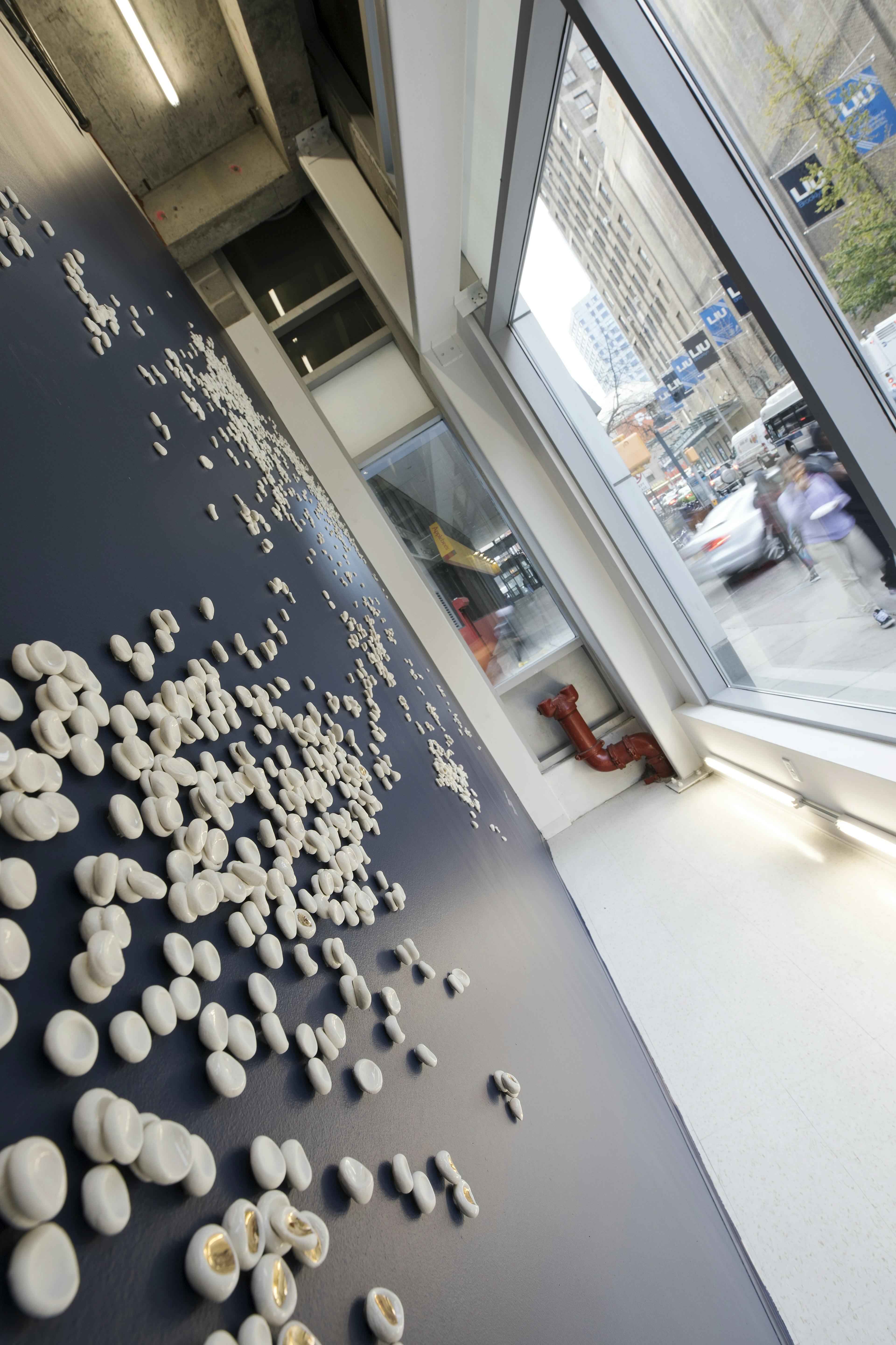 Sideways angle of artist Christina Watka's custom wall installation made from an assortment of white, hand-sculpted porcelain pieces.
