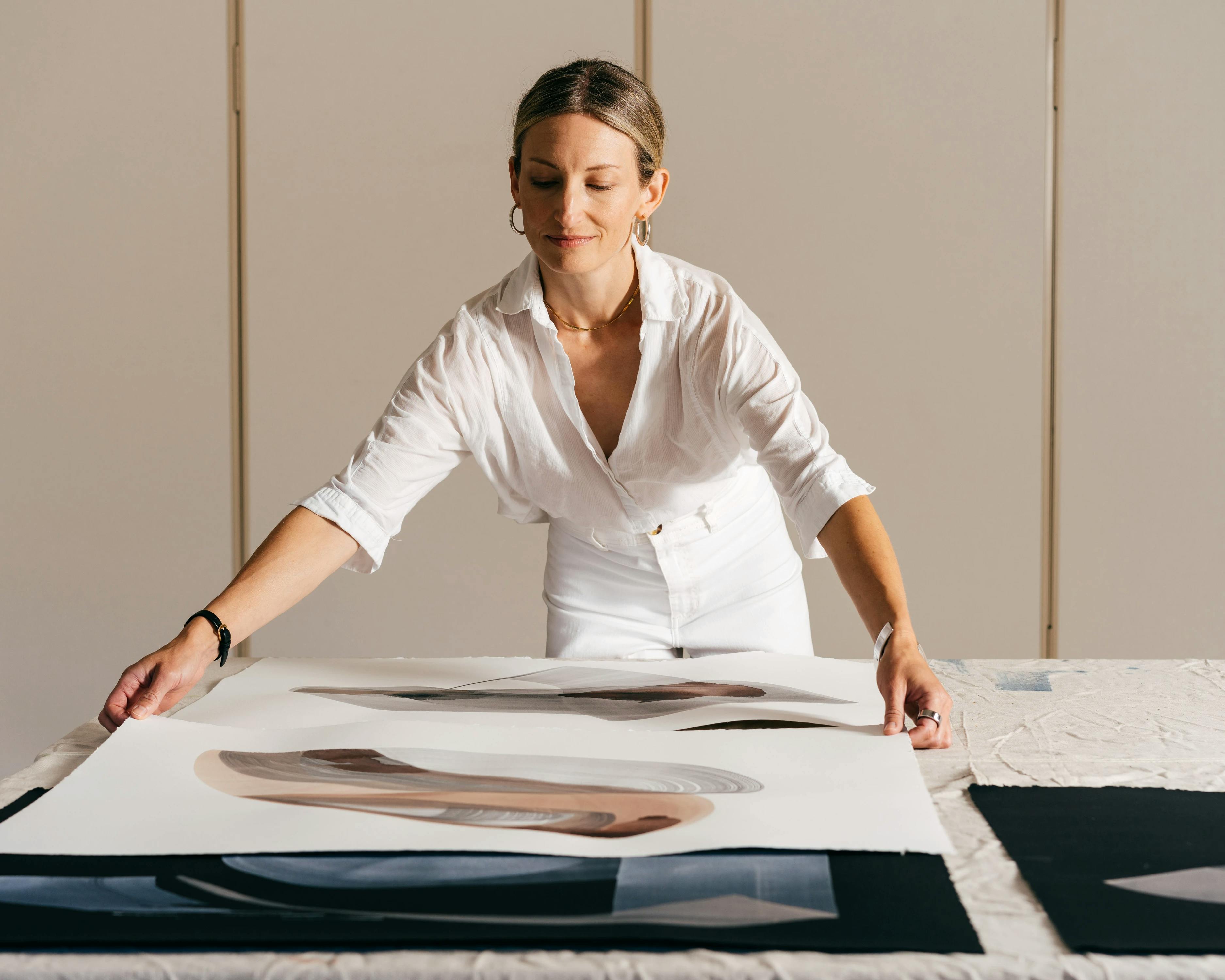 Artist Laura Naples moves large paintings on paper across a table at MacArthur Place.