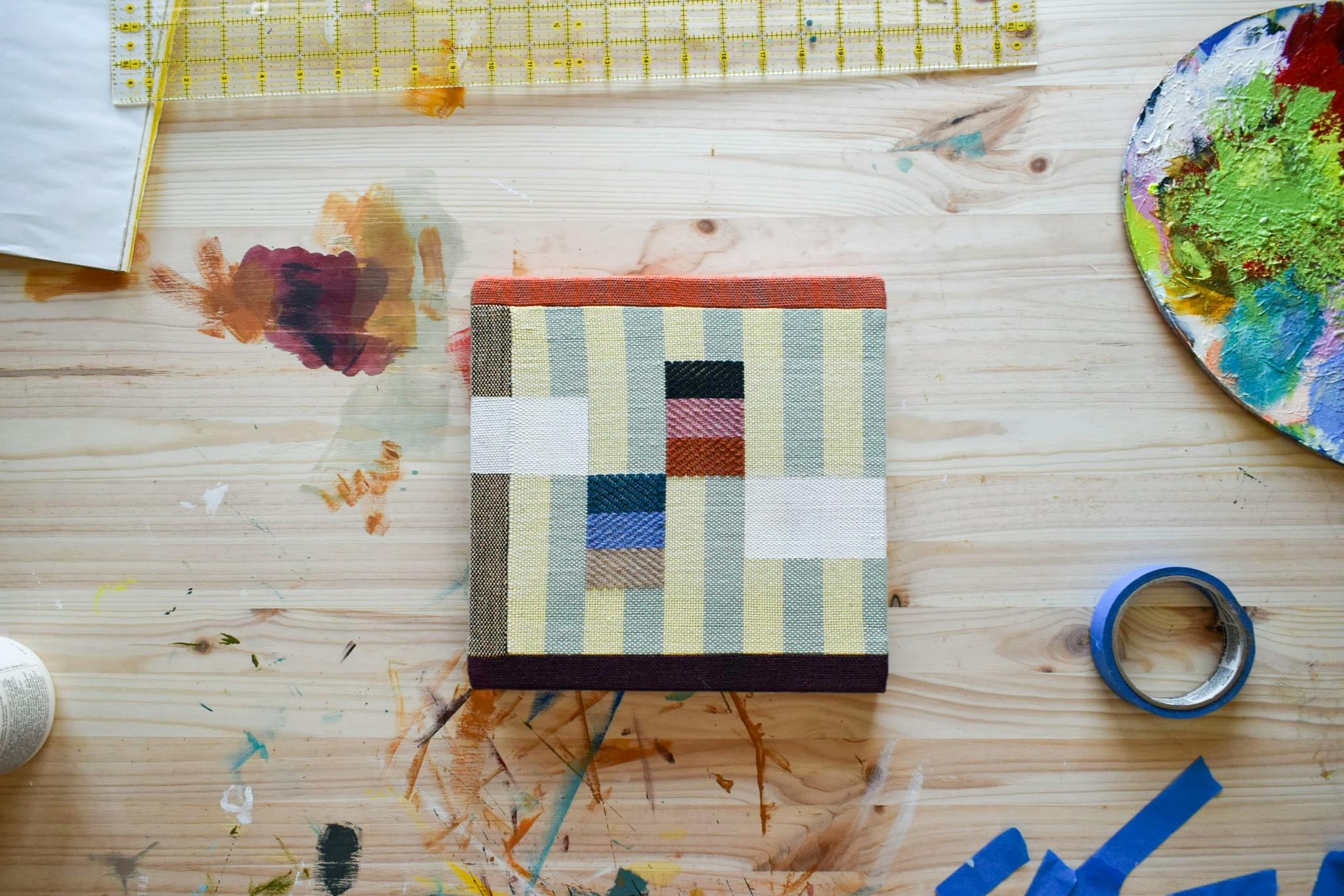 A small, striped acrylic painting on handwoven textiles by artist Sarah Sullivan Sherrod.