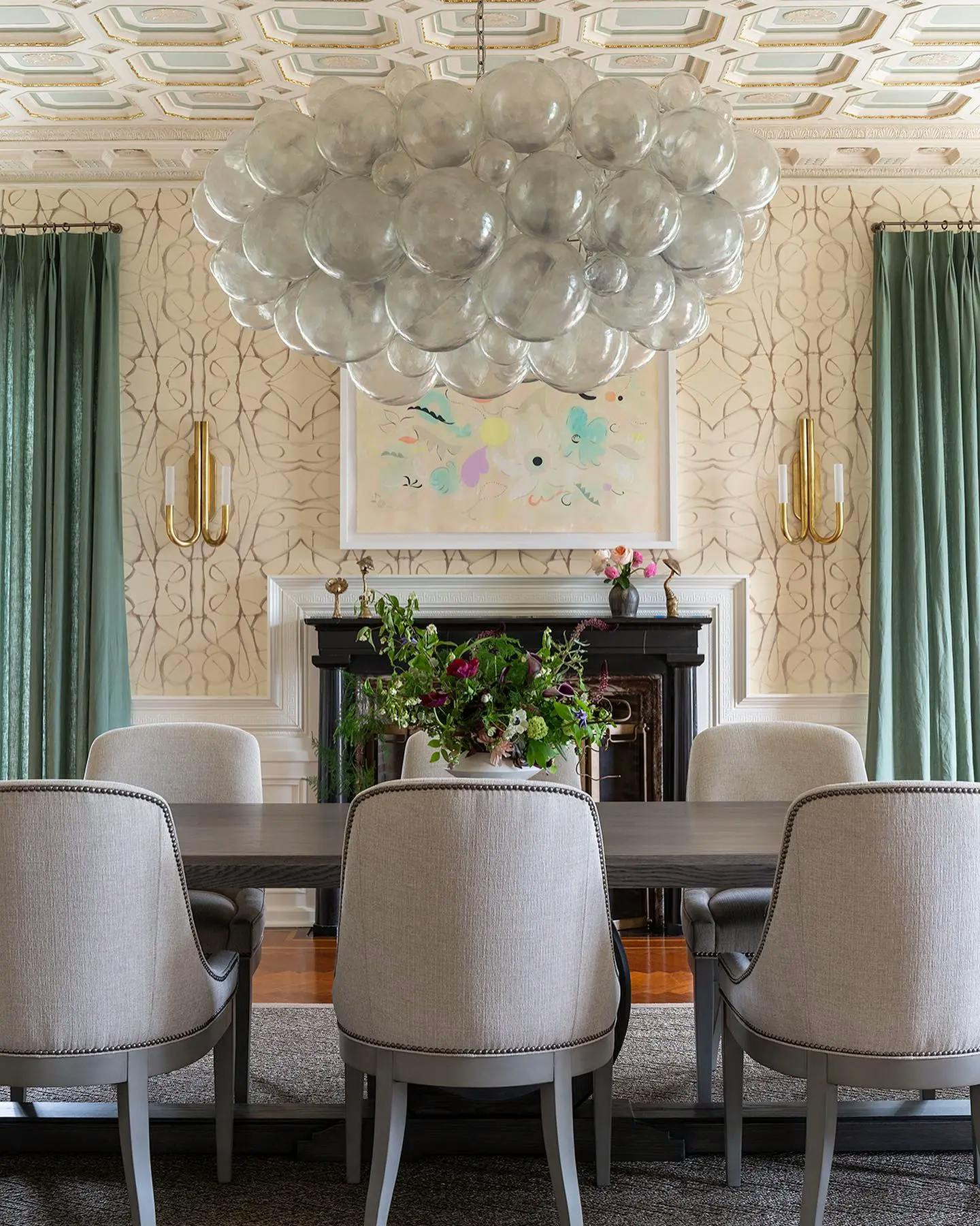 A floral painting by artist Kayla Plosz Antiel installed above a fireplace in a dining room.