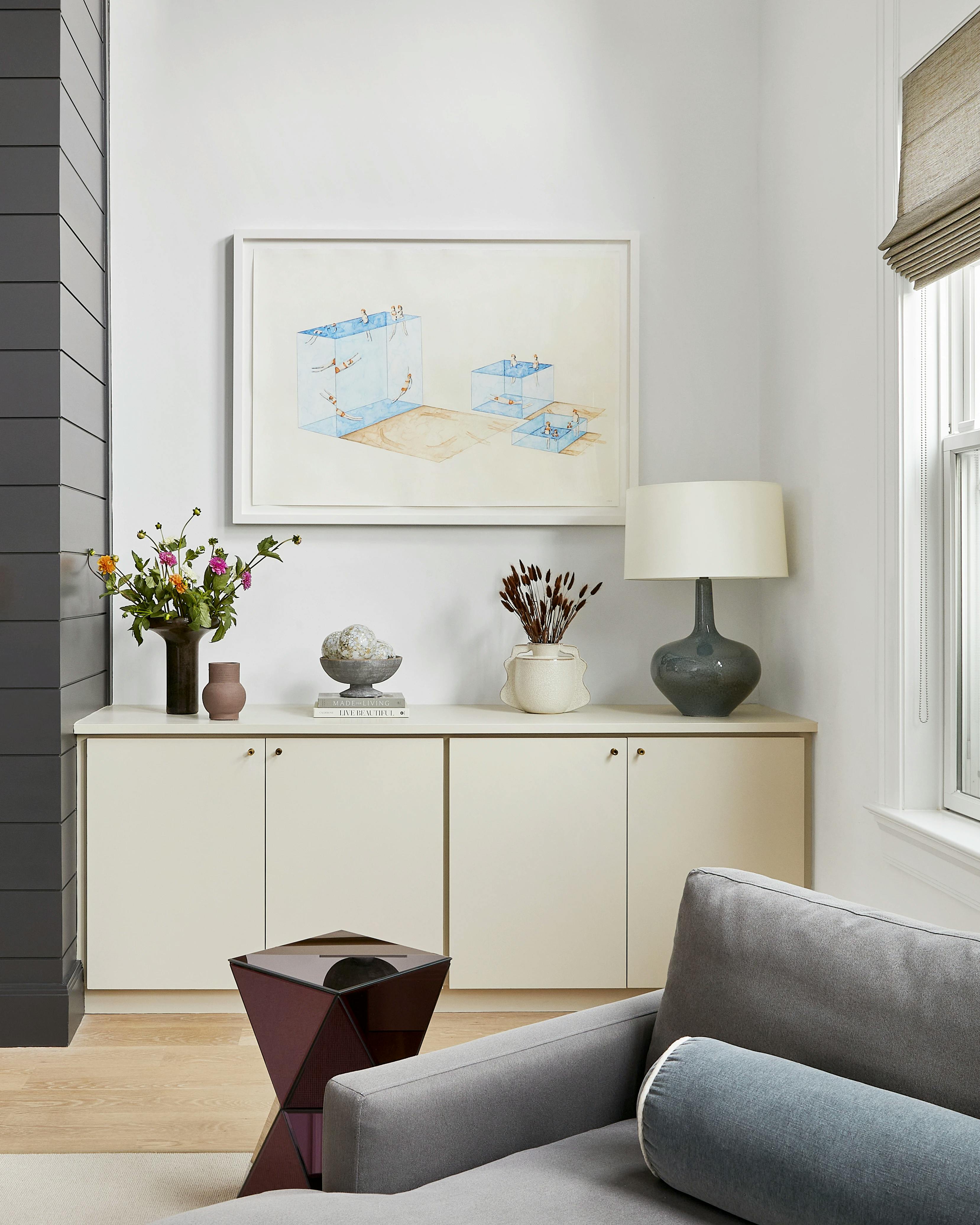 Framed painting on paper by Eddie K installed above a white credenza in a space designed by Alive + Kicking Design.