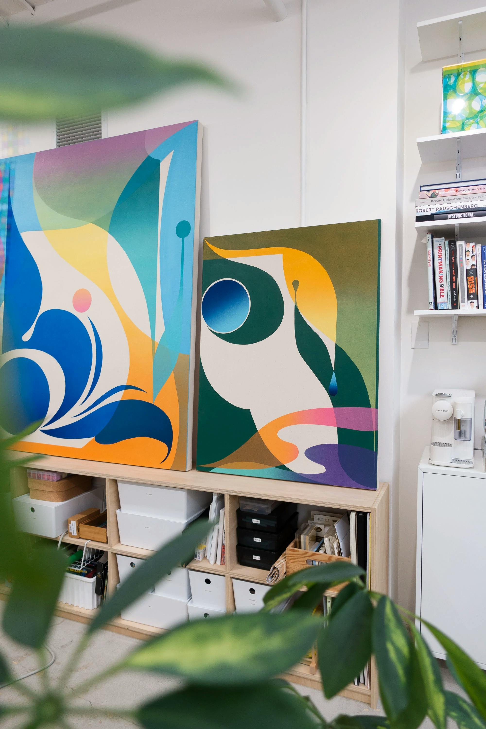 An abstract, geometric painting by artist Erin Zhao on top of a wooden storage unit in her studio.