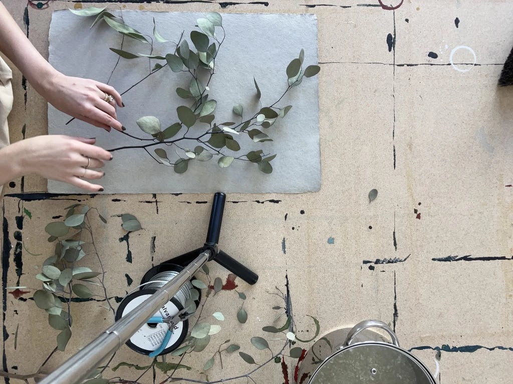 Artist Kate Roebuck arranging twigs and leaves on a piece of paper in her studio.