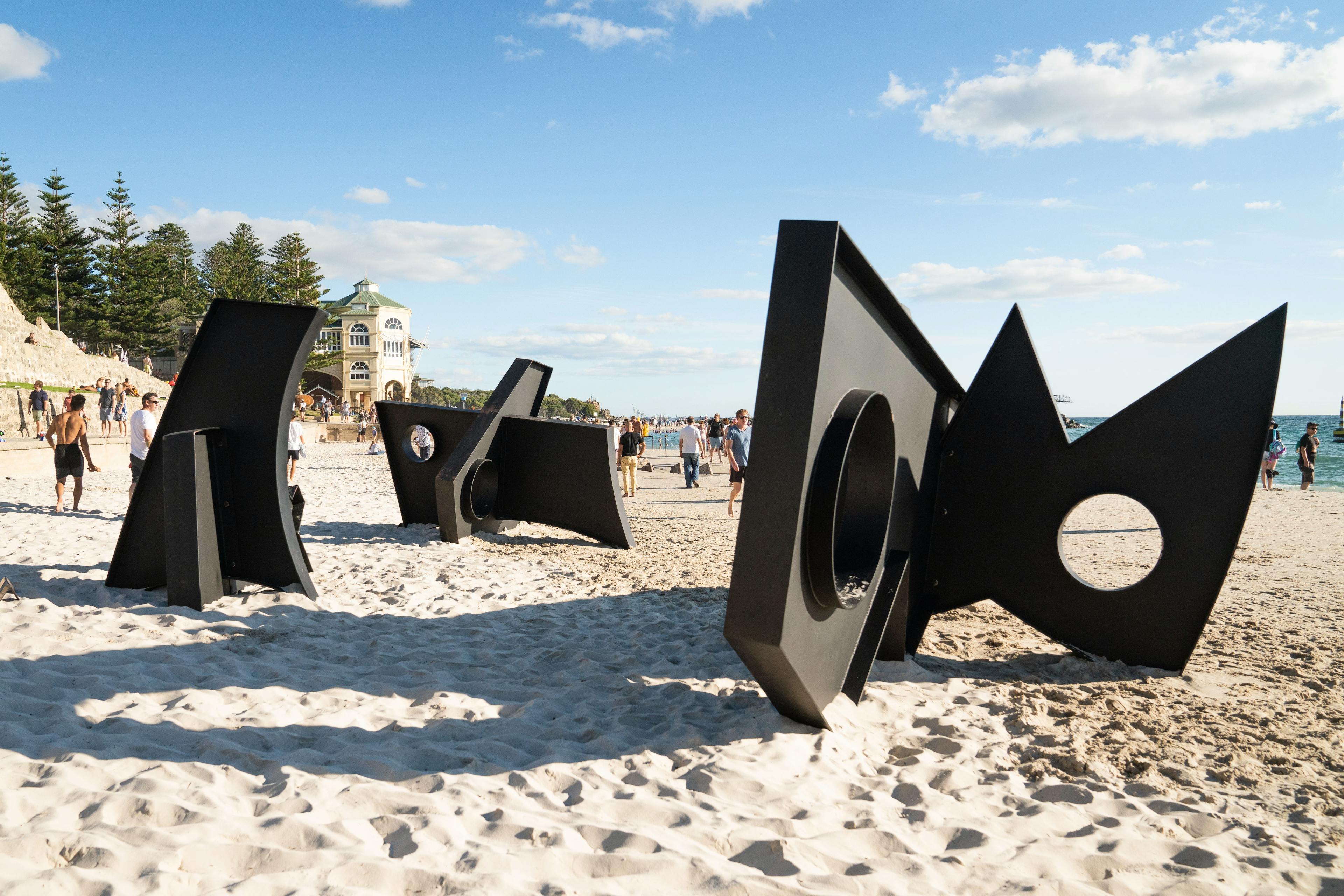 Three, oversized black metal sculptures by artist Fitzhugh Karol on a beach in Australia.